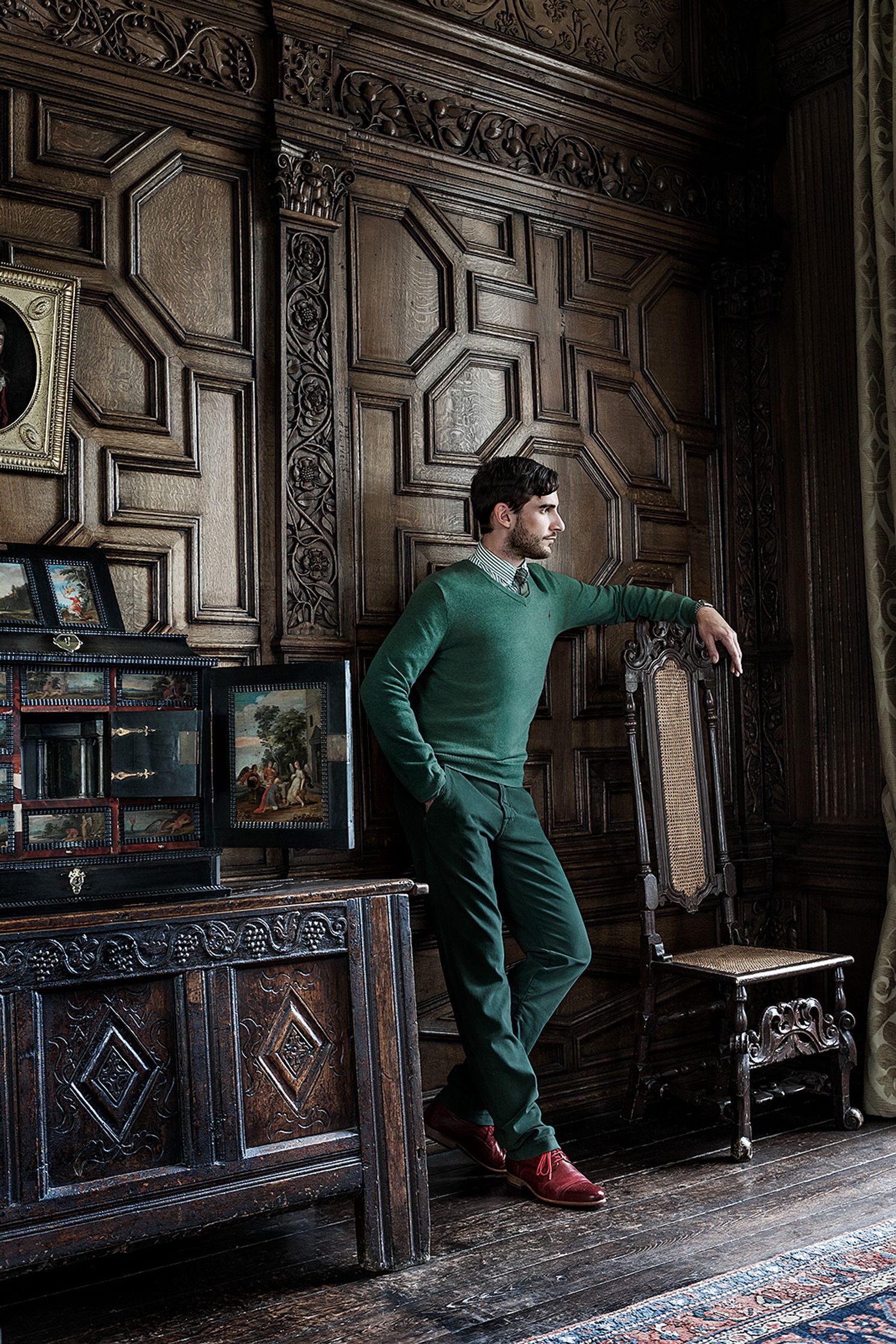 a man leaning against a chair in an ornate room creative post production