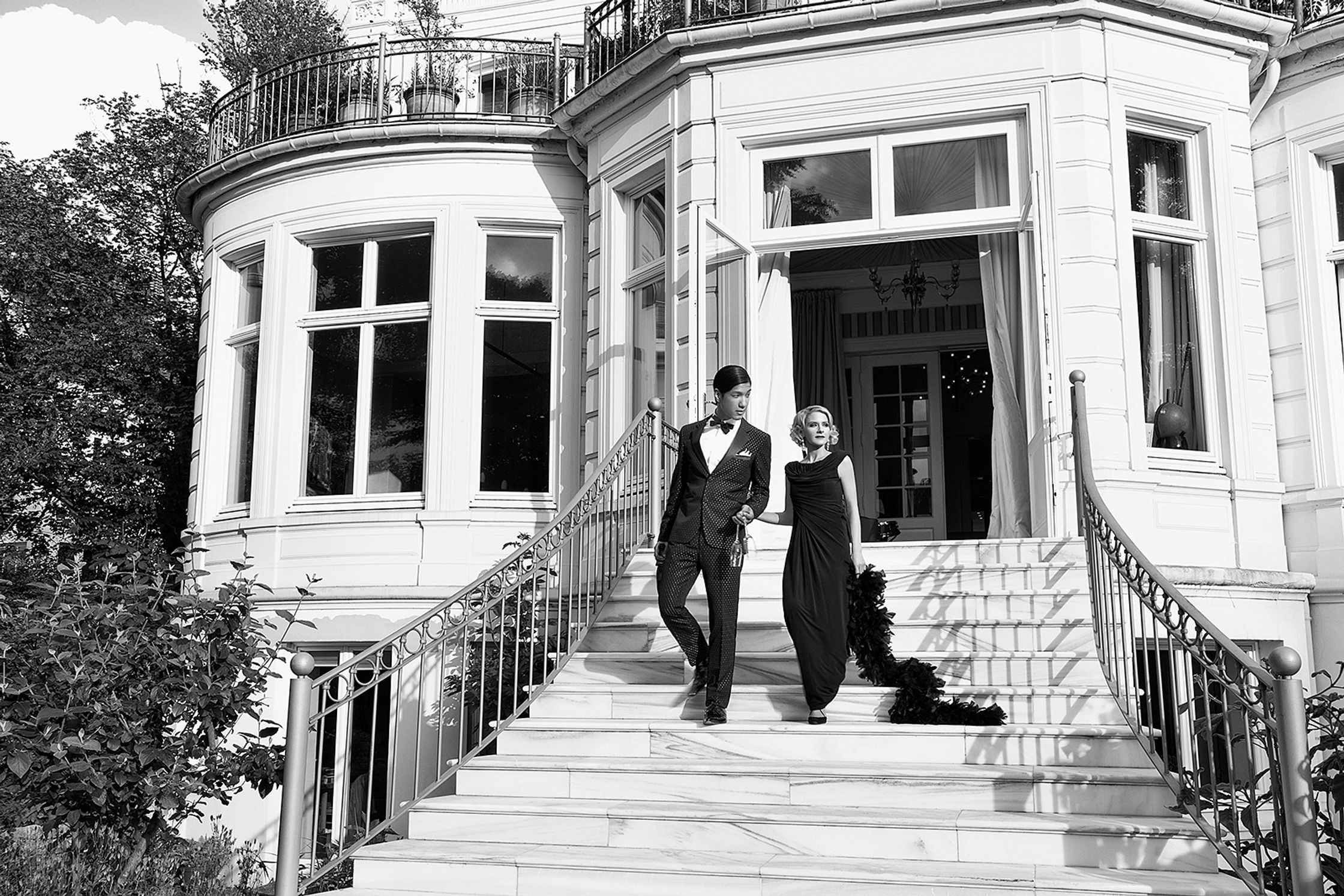 a black and white photo of a couple on the steps of a mansion advertising retouch hamburg