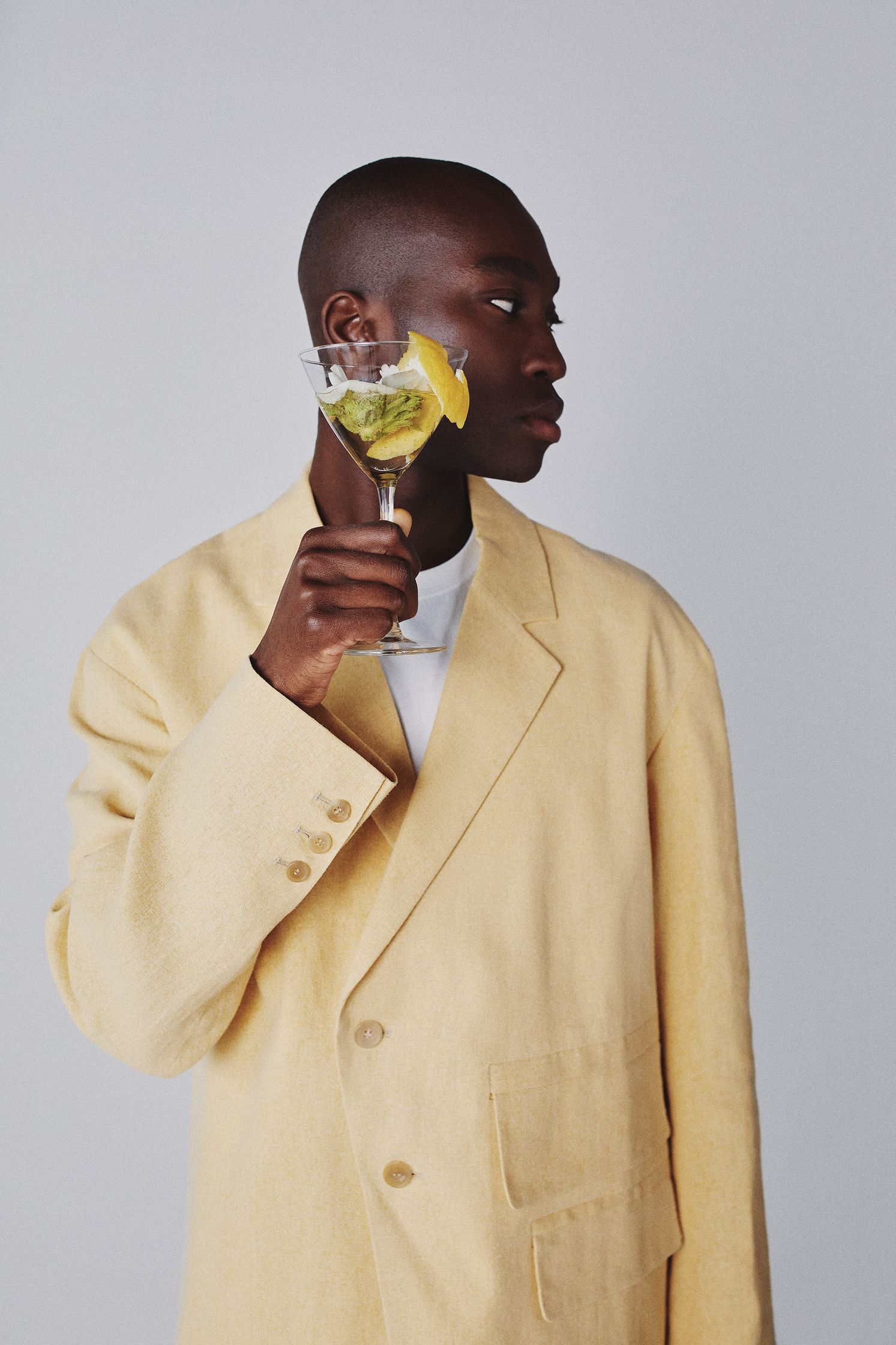 a man in a yellow suit holding a glass of lemon juice