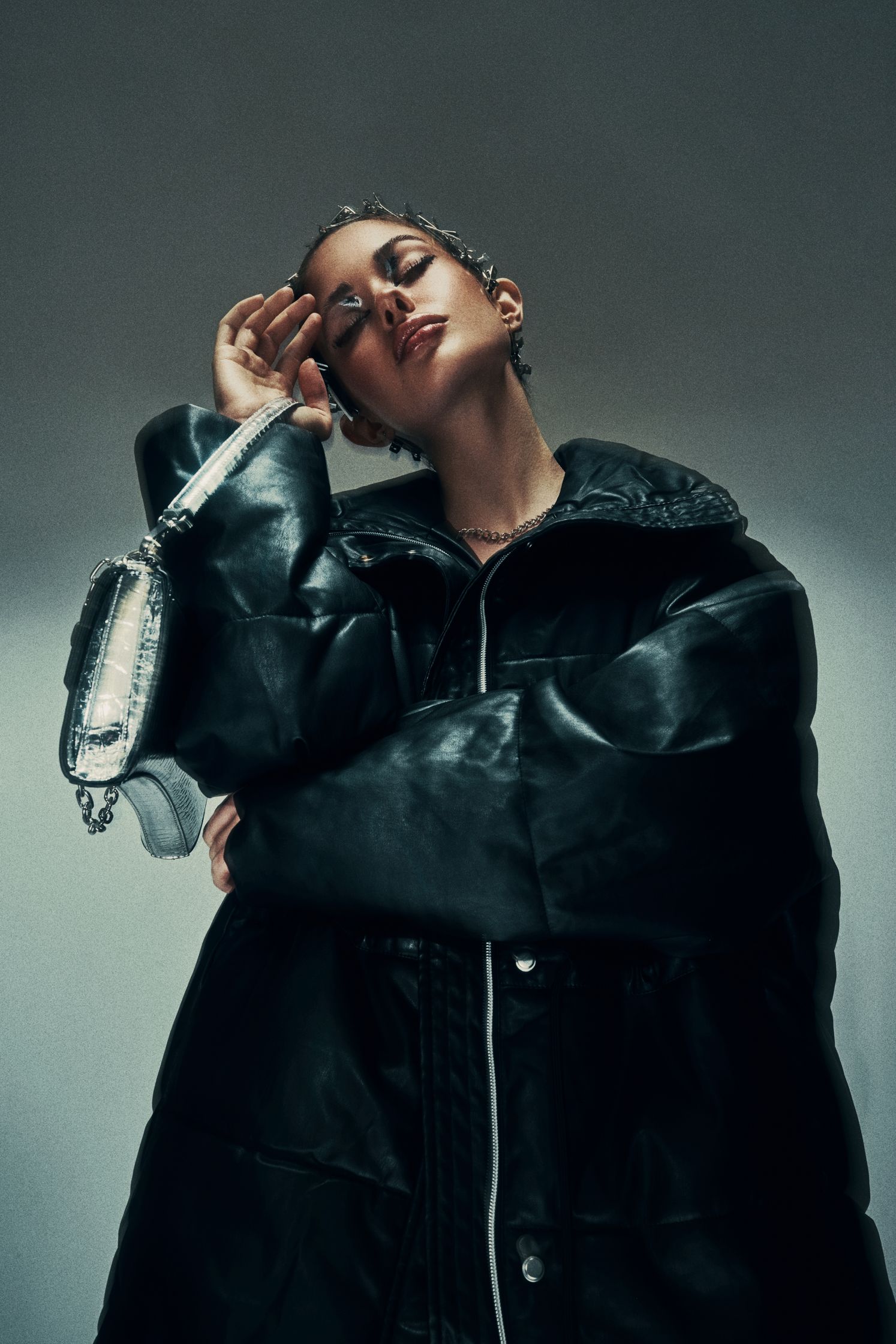 Full-body shot of Monique Bourscheid in a black oversized jacket, posing with a silver handbag.