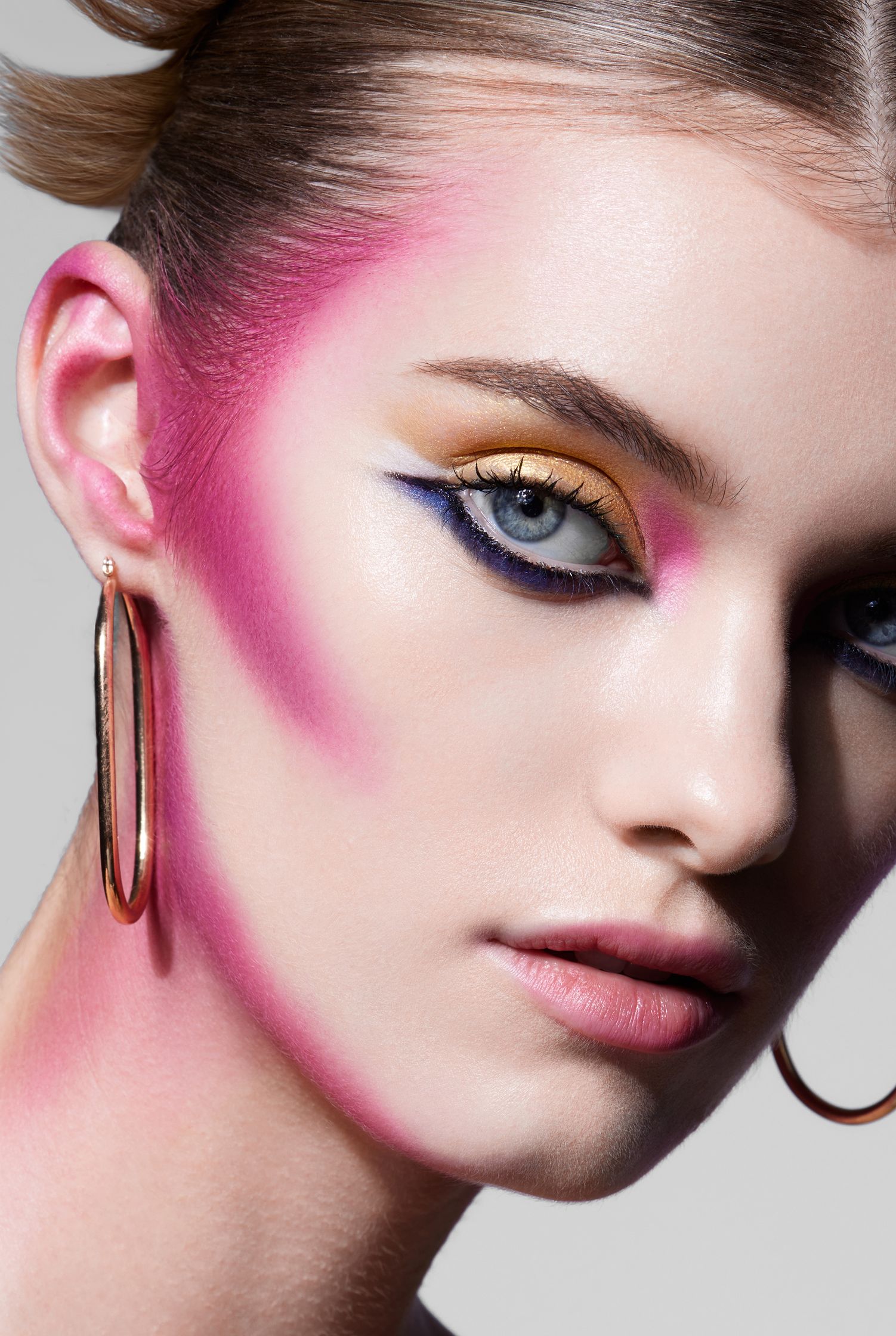 a model with bright pink makeup and hoop earrings