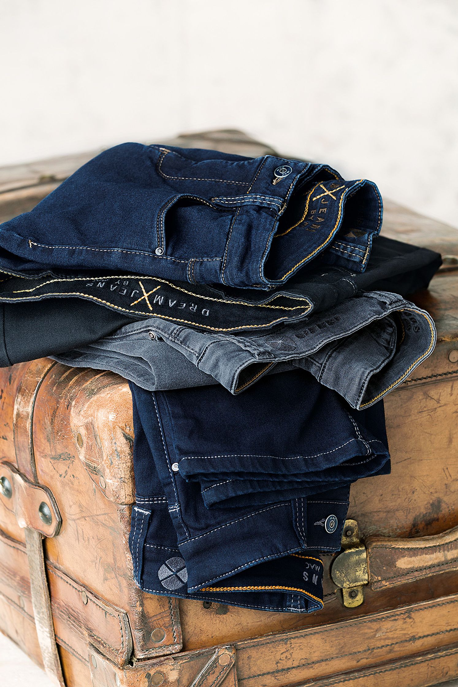 a pair of blue jeans stacked on top of a suitcase - Bildbearbeitung Hamburg