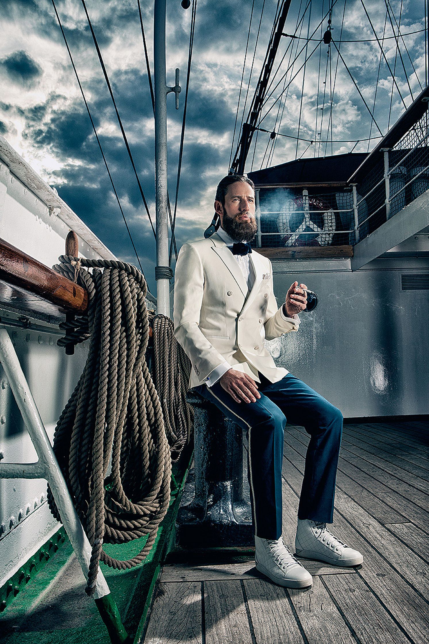 a man with a beard sitting on the deck of a boat Creative Retouching Hamburg