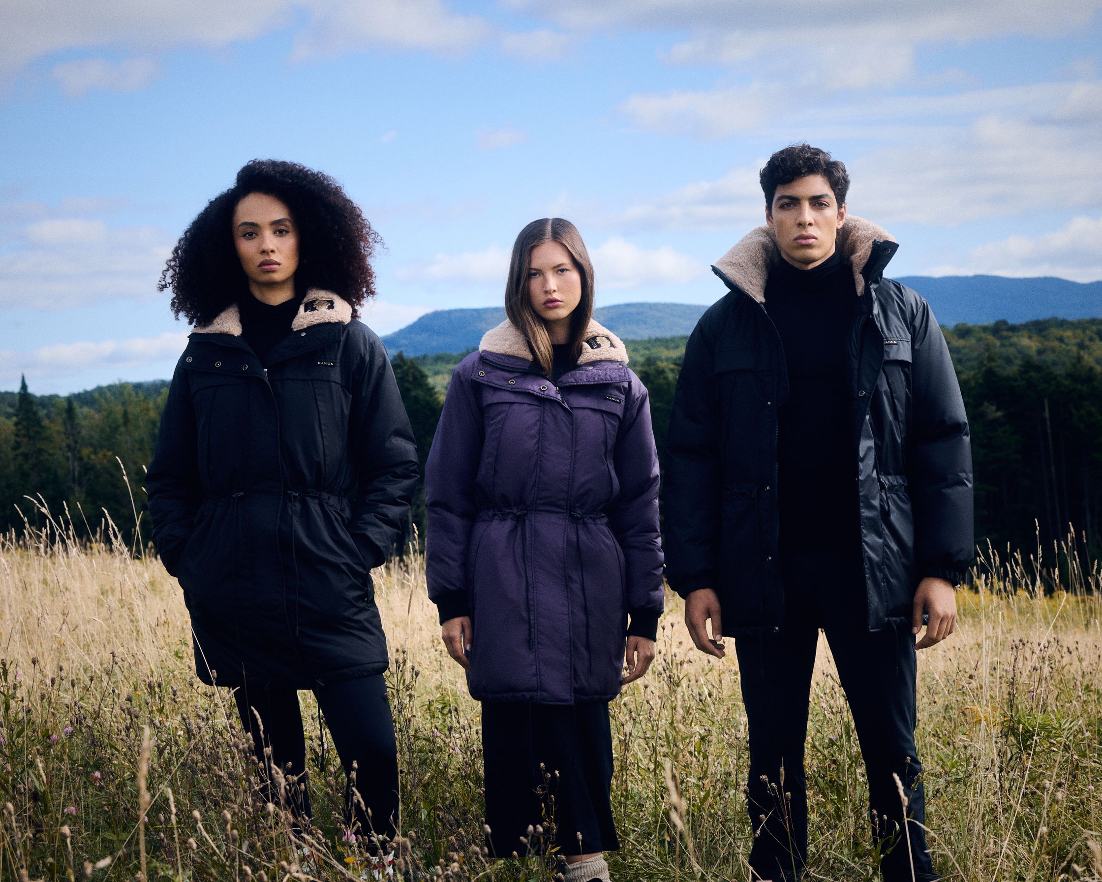 three people standing in a field wearing down jackets