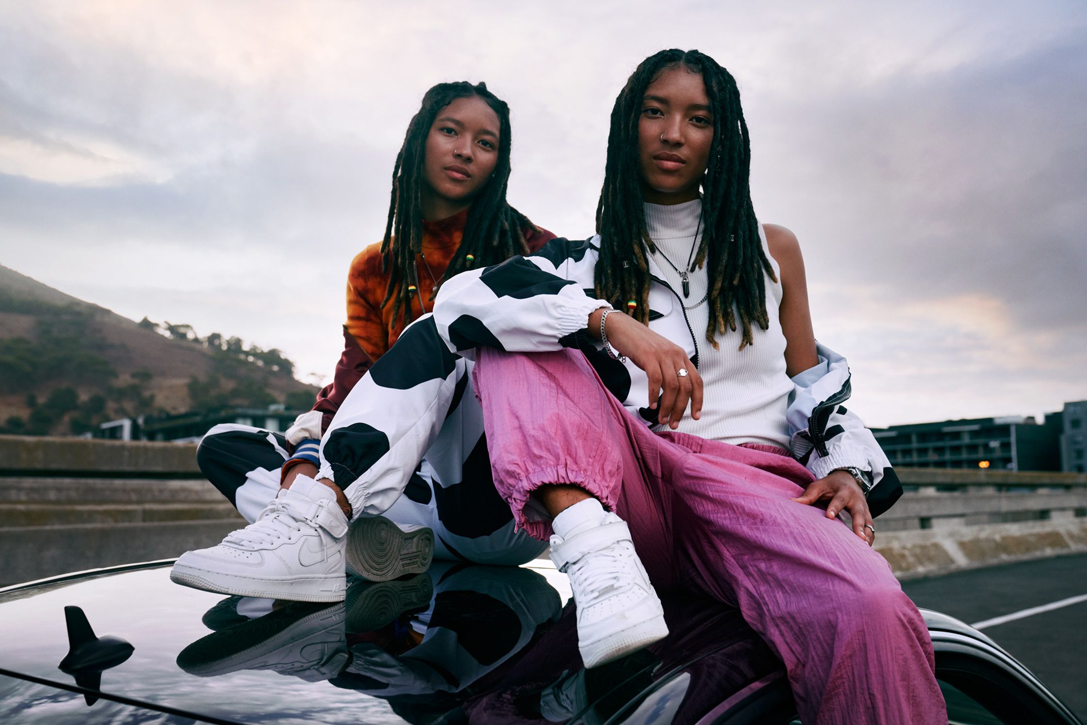 two asian women sitting on top of a car