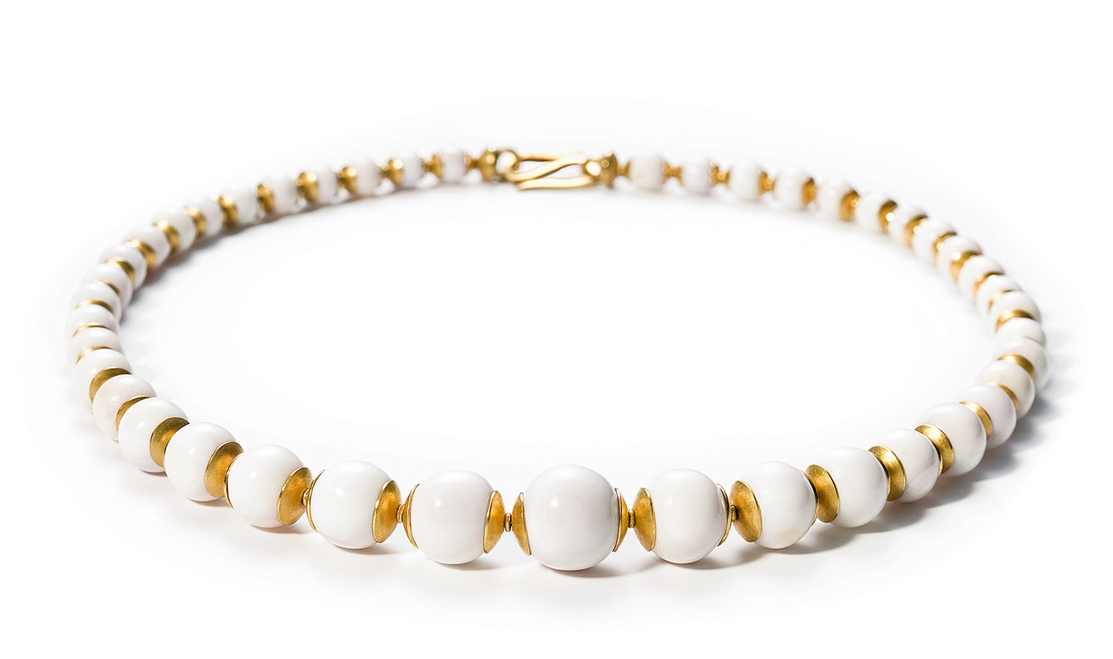 a white and gold necklace with white beads Retouch - Bildbearbeitung Hamburg