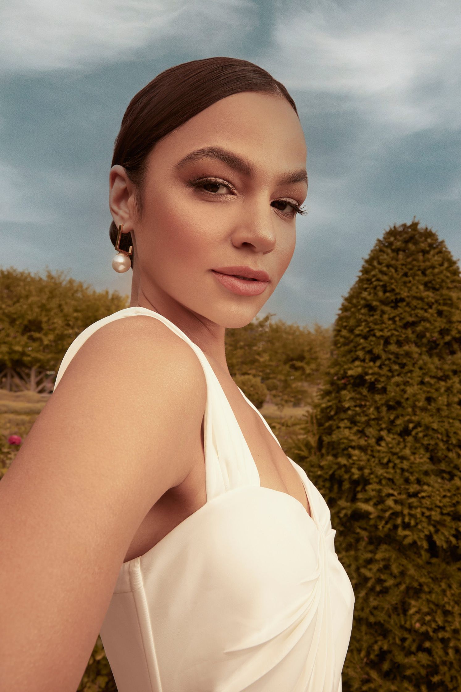 a woman is posing for a photo in a white dress