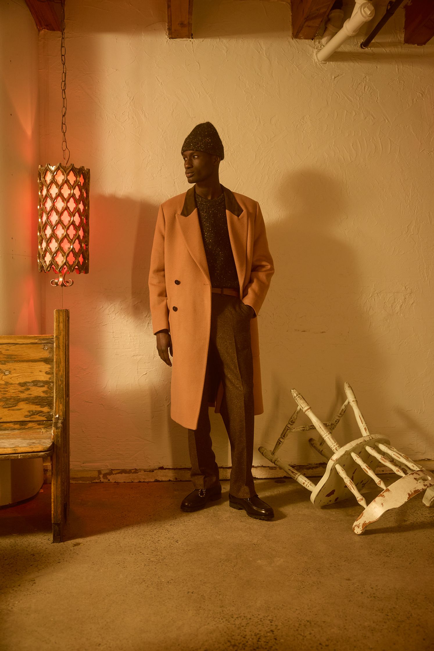 a man in a coat standing next to a chair