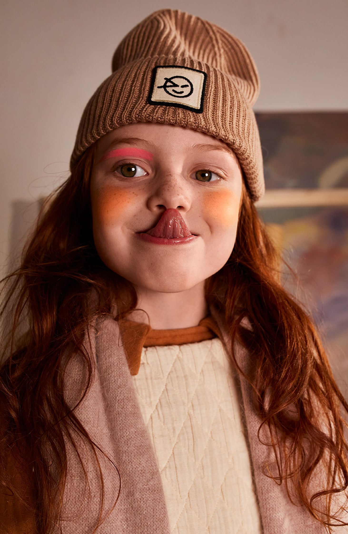 a little girl wearing a beanie and lipstick