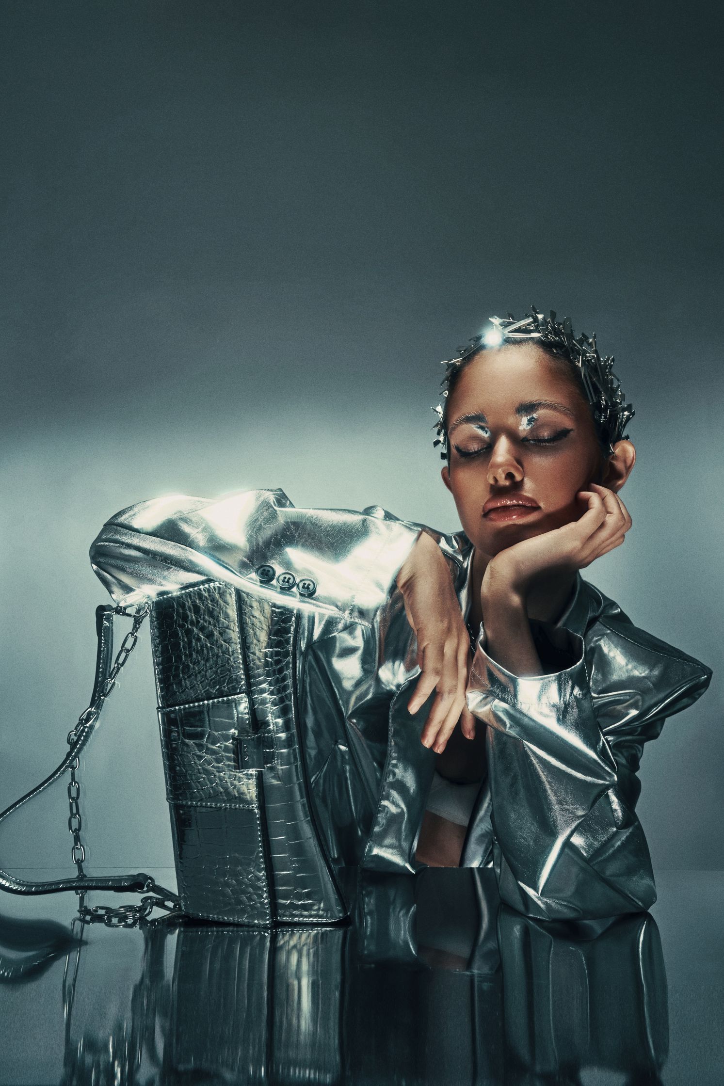 Editorial shot of Monique Bourscheid in a silver jacket and metallic accessories, showcasing avant-garde fashion styling.