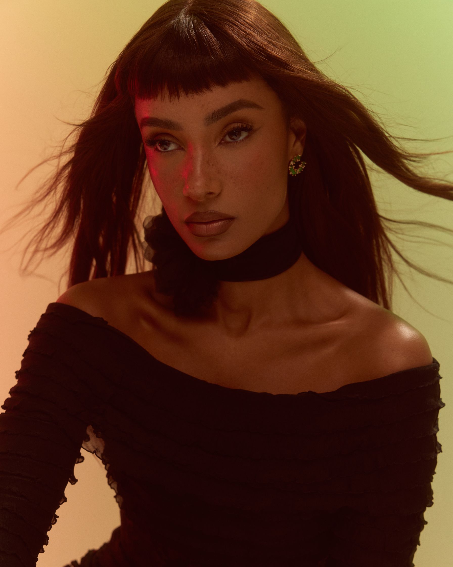 a black woman with long hair posing in front of a colorful background