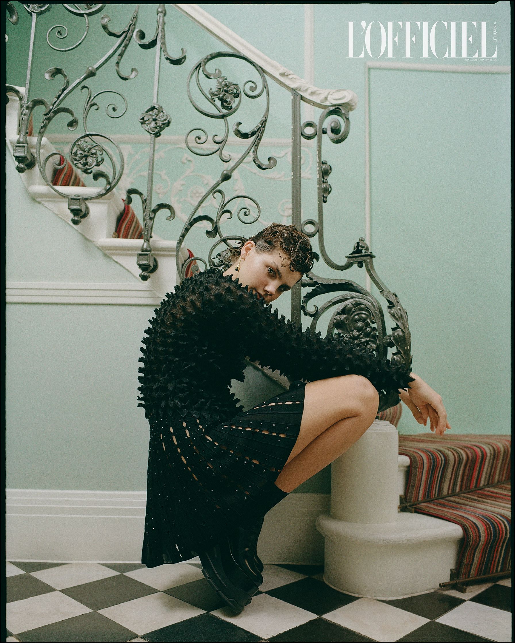 a woman is sitting on a staircase in a black dress