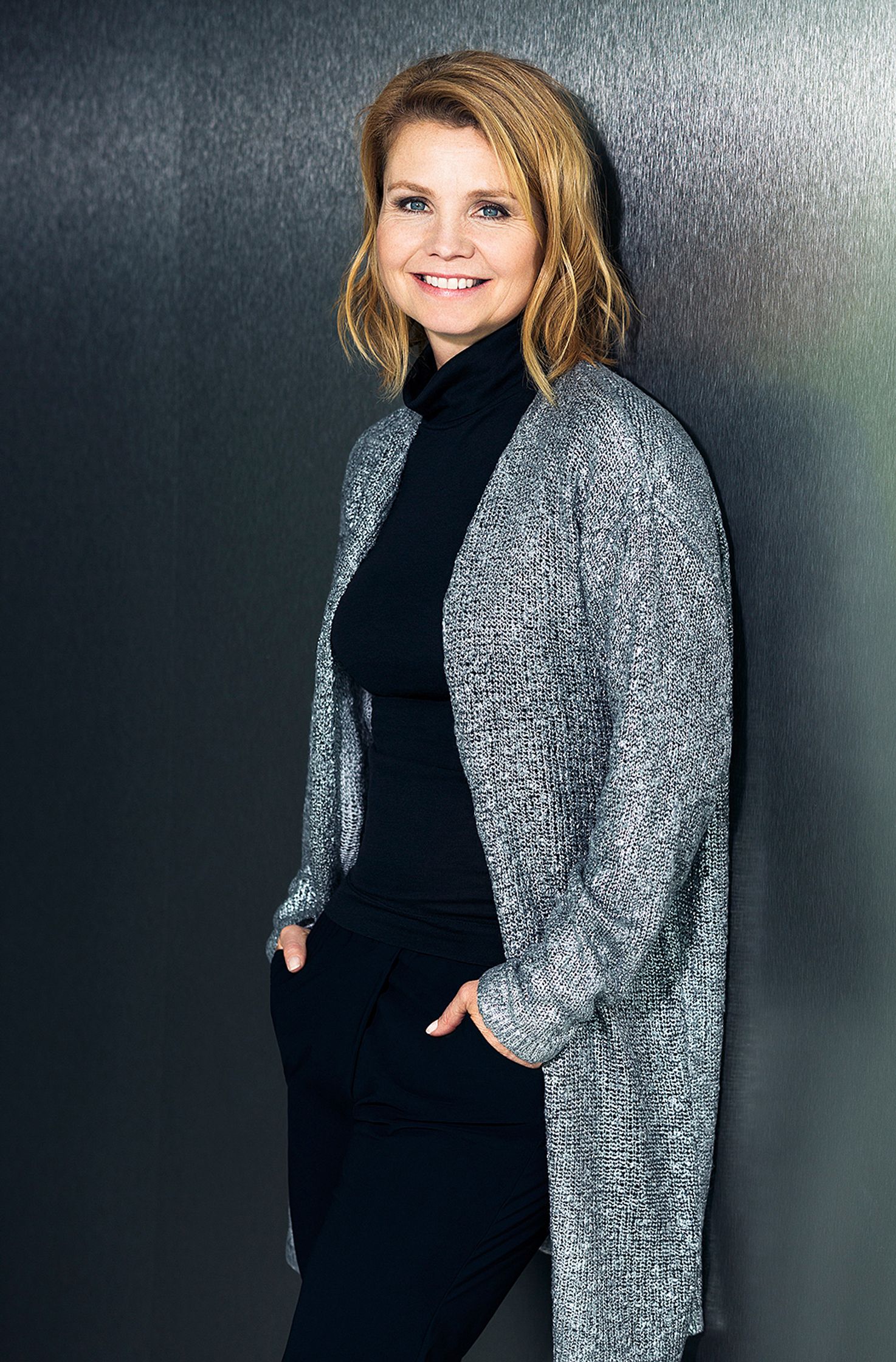 annette frier in black pants and a grey cardigan is leaning against a wall
Retouch - Bildbearbeitung Hamburg