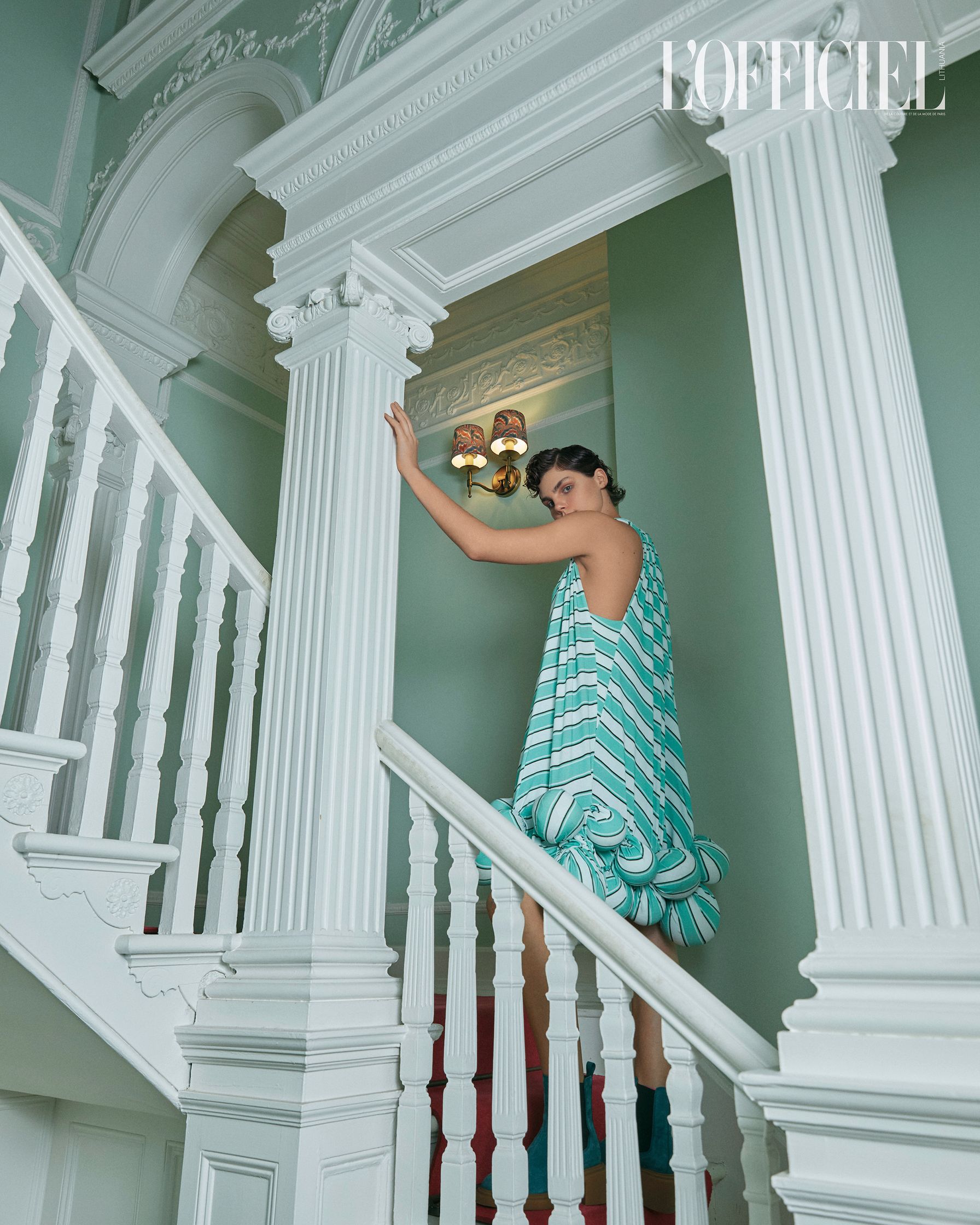 a woman is standing on a staircase in a white dress