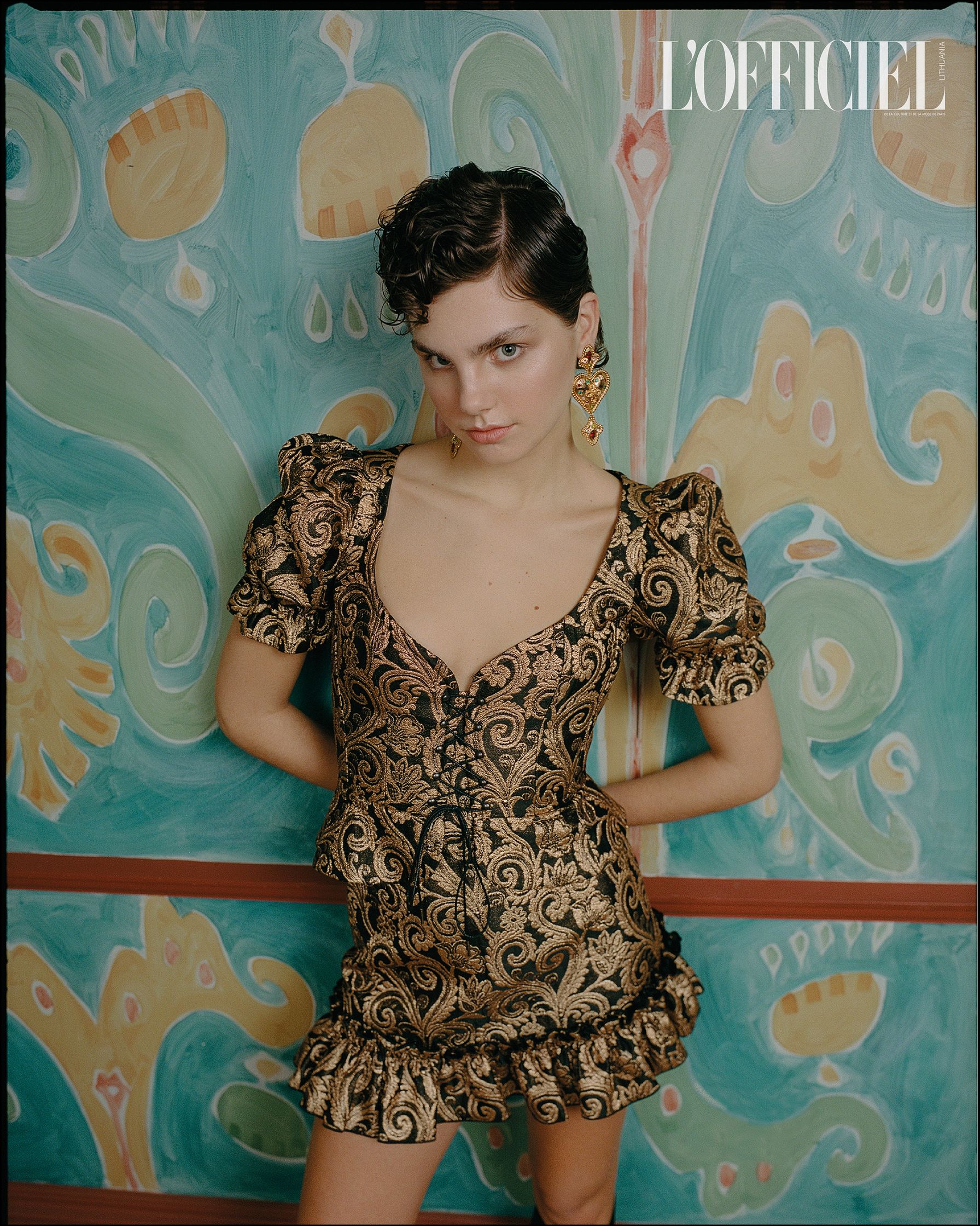 a woman in a gold dress posing in front of a wall