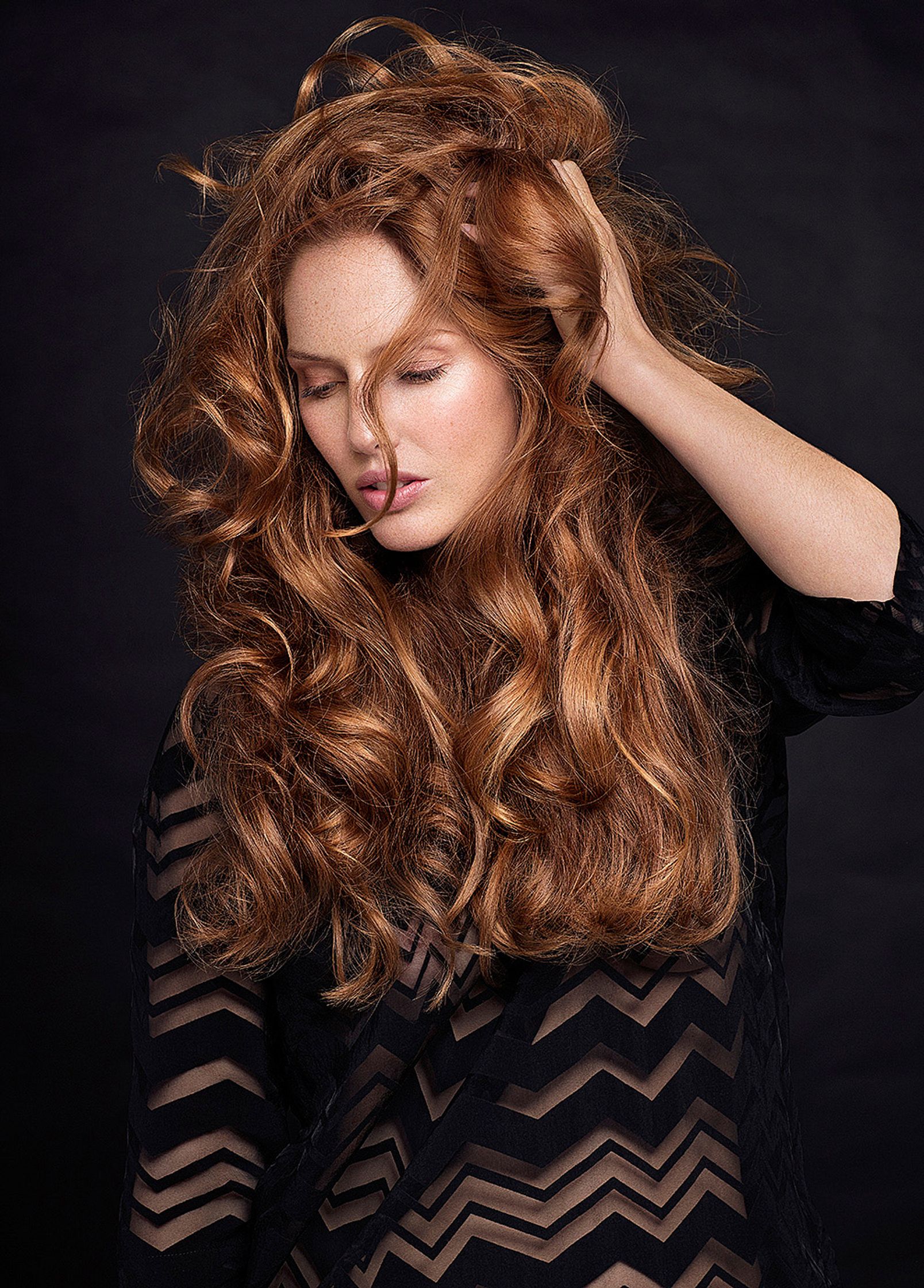 a woman with long red hair posing on a black background hair retouche hamburg