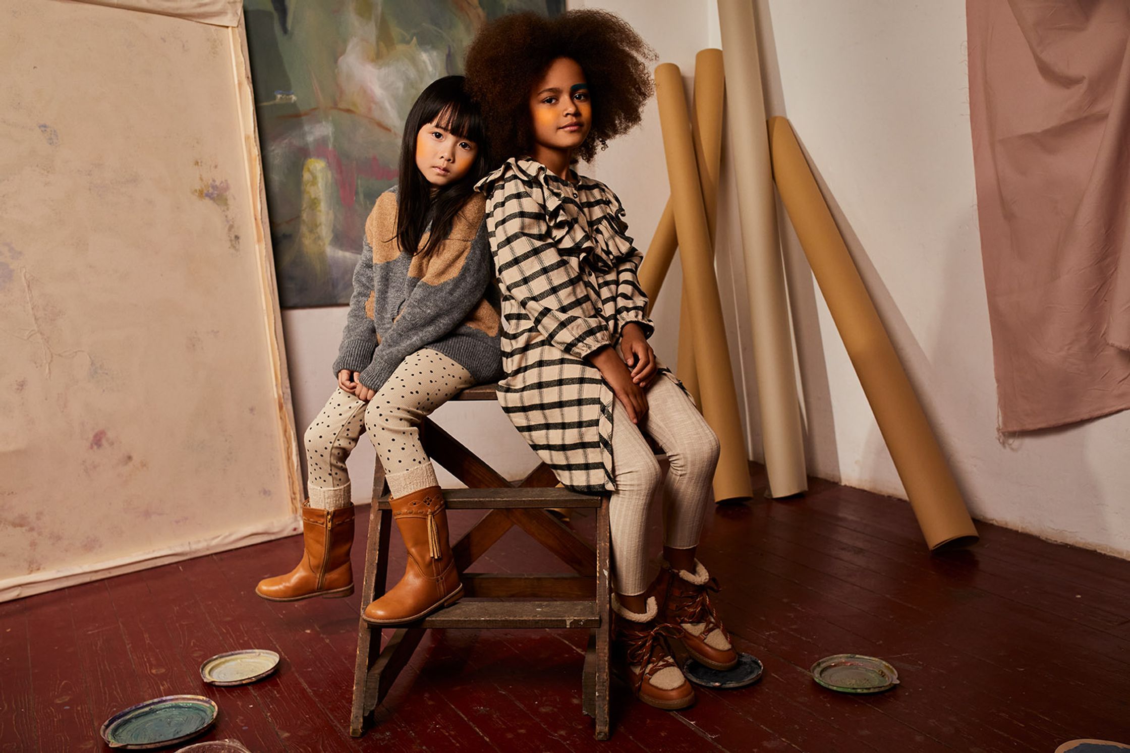 two girls sitting on a chair in an art studio