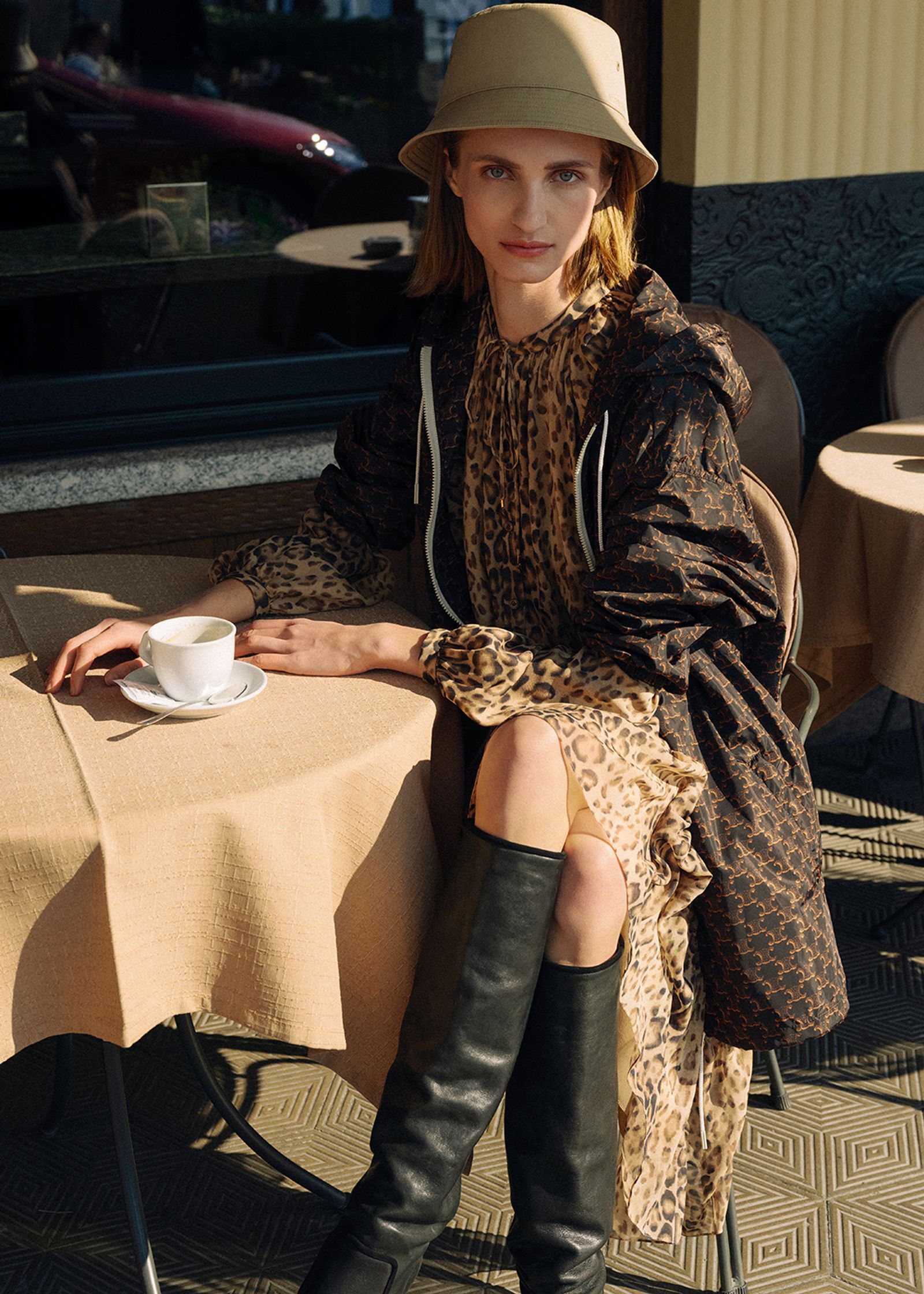 a woman sitting at a table with a cup of coffee