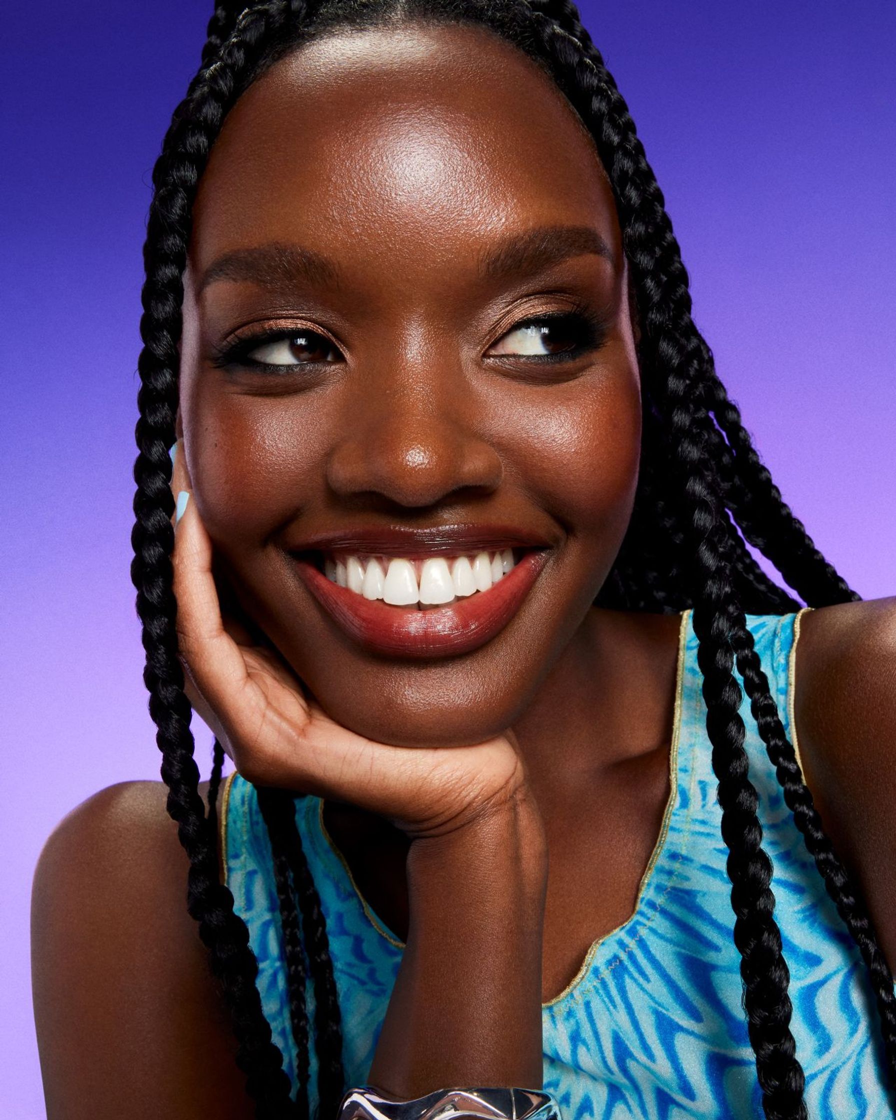 a young black woman smiling with her hand on her chin