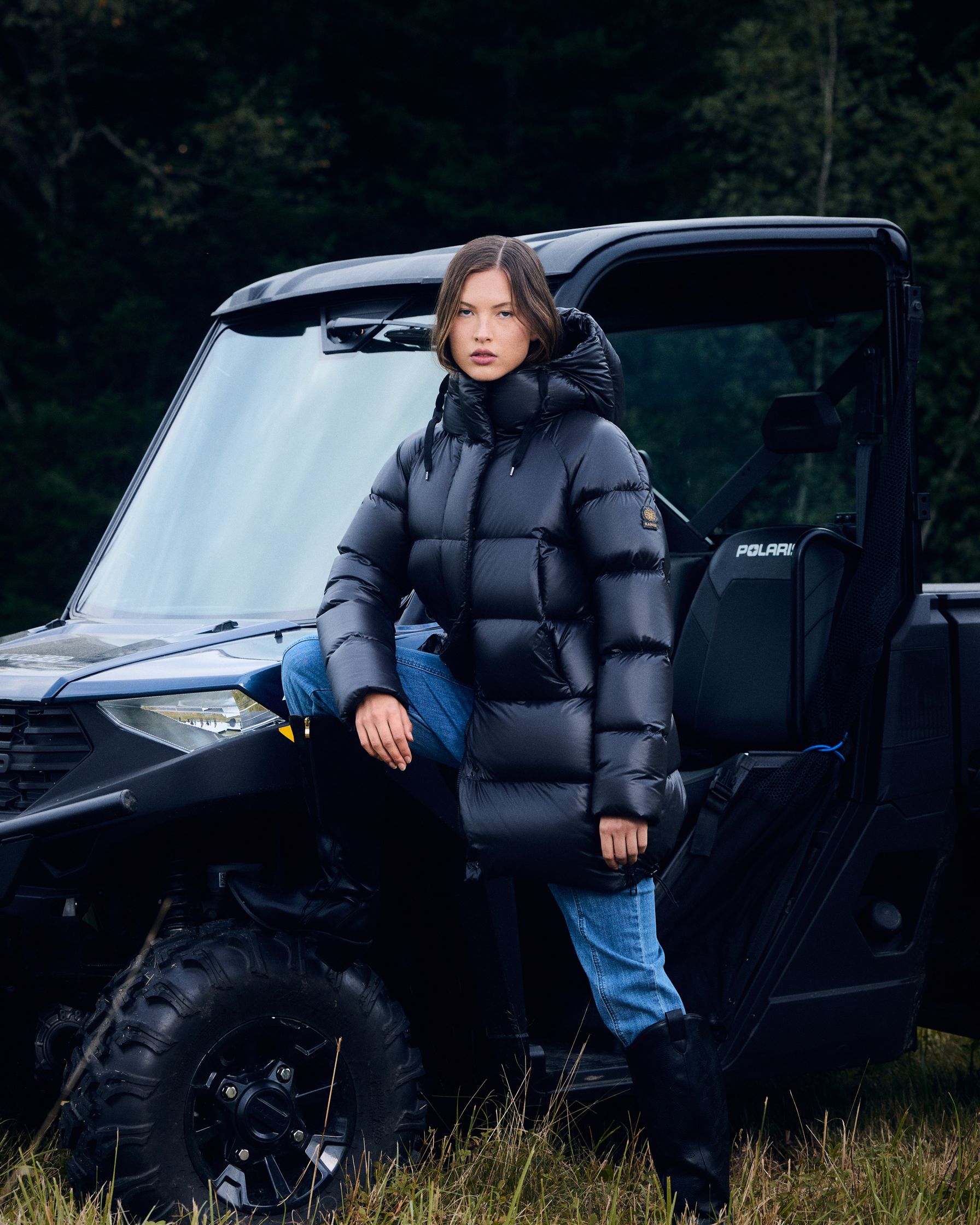 a woman is posing next to an atv in a field