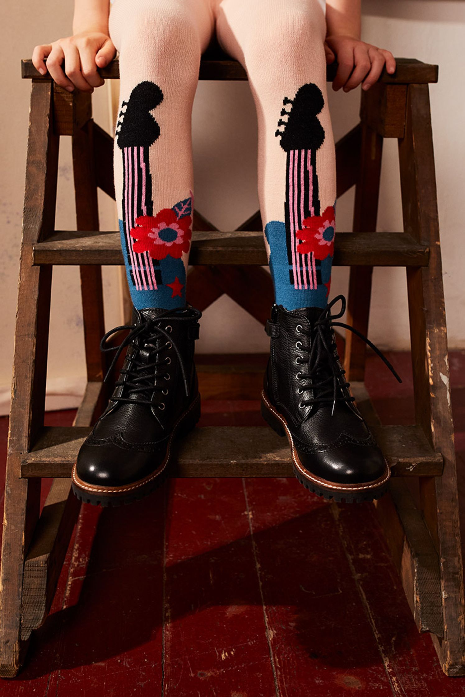 a child wearing a pair of socks with a guitar on them