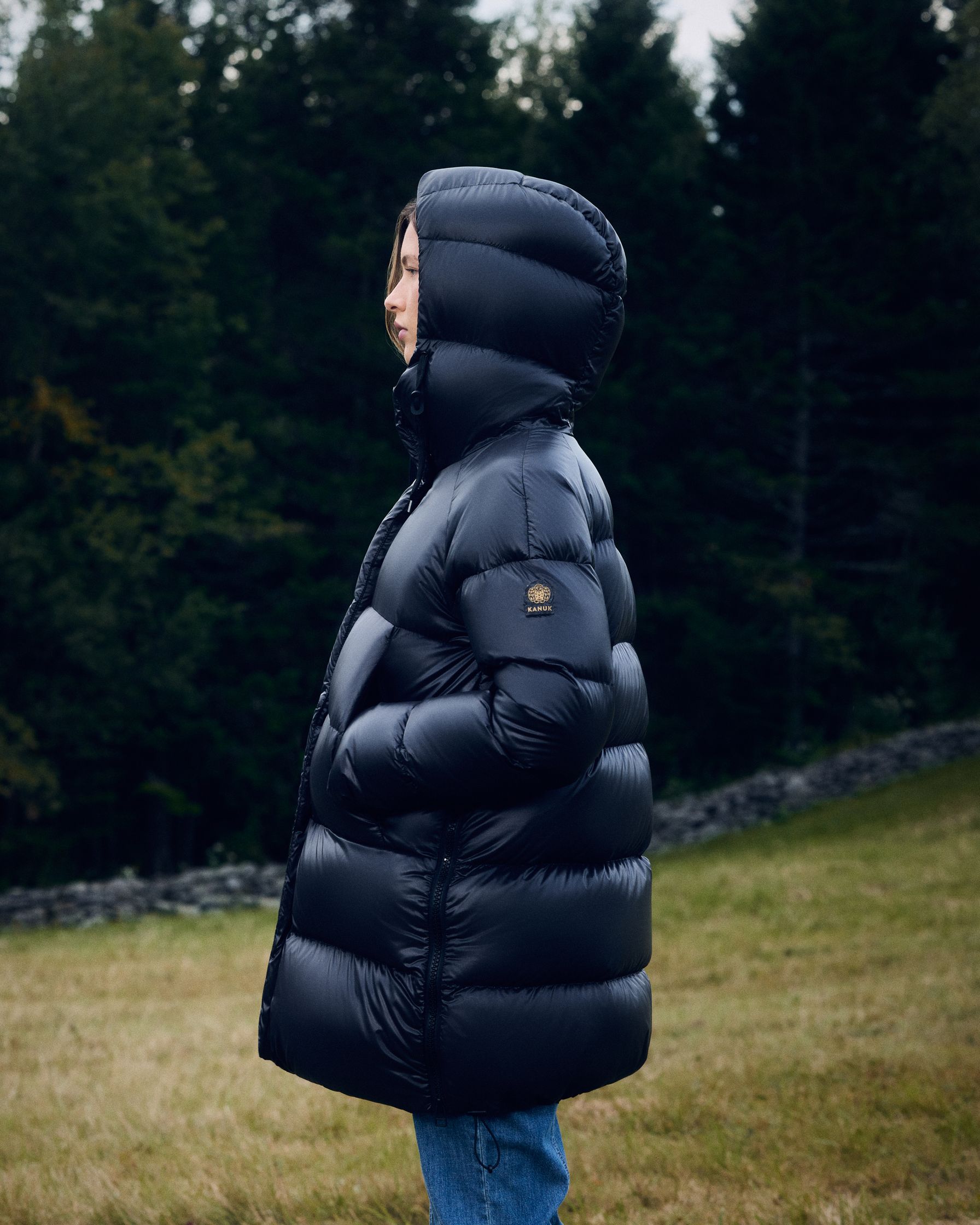 a woman in a black puffer jacket standing in a field