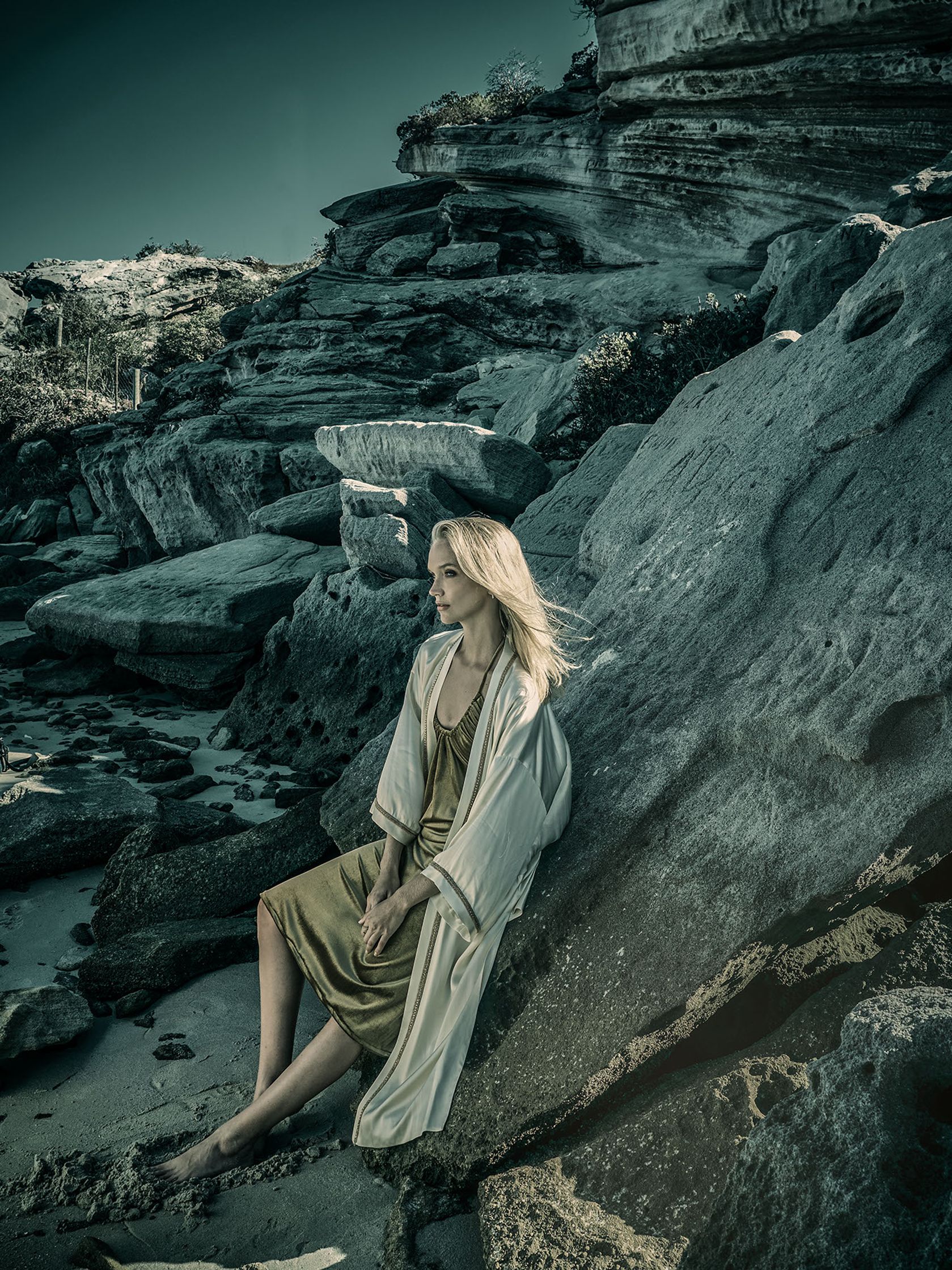 a woman in a robe sitting on a rock