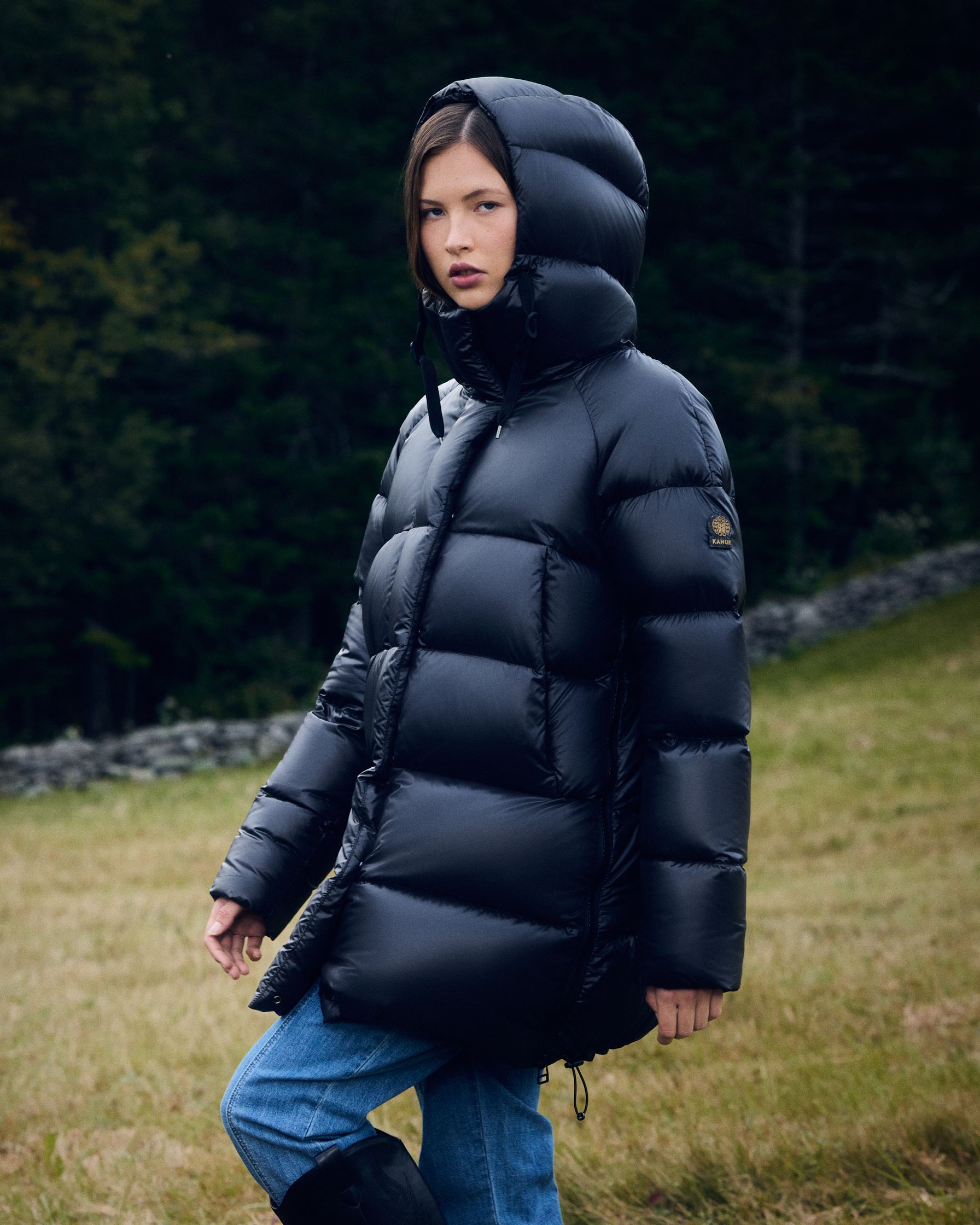 a woman in a black puffer jacket standing in a field