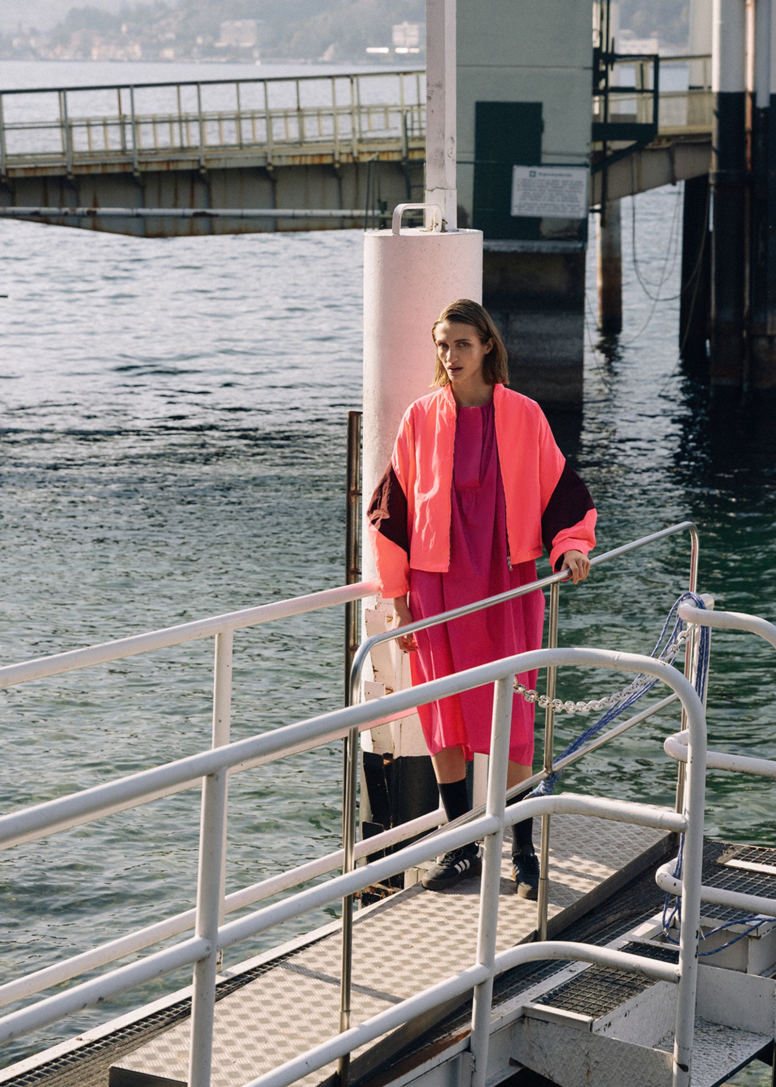 a woman standing on a pier near the water