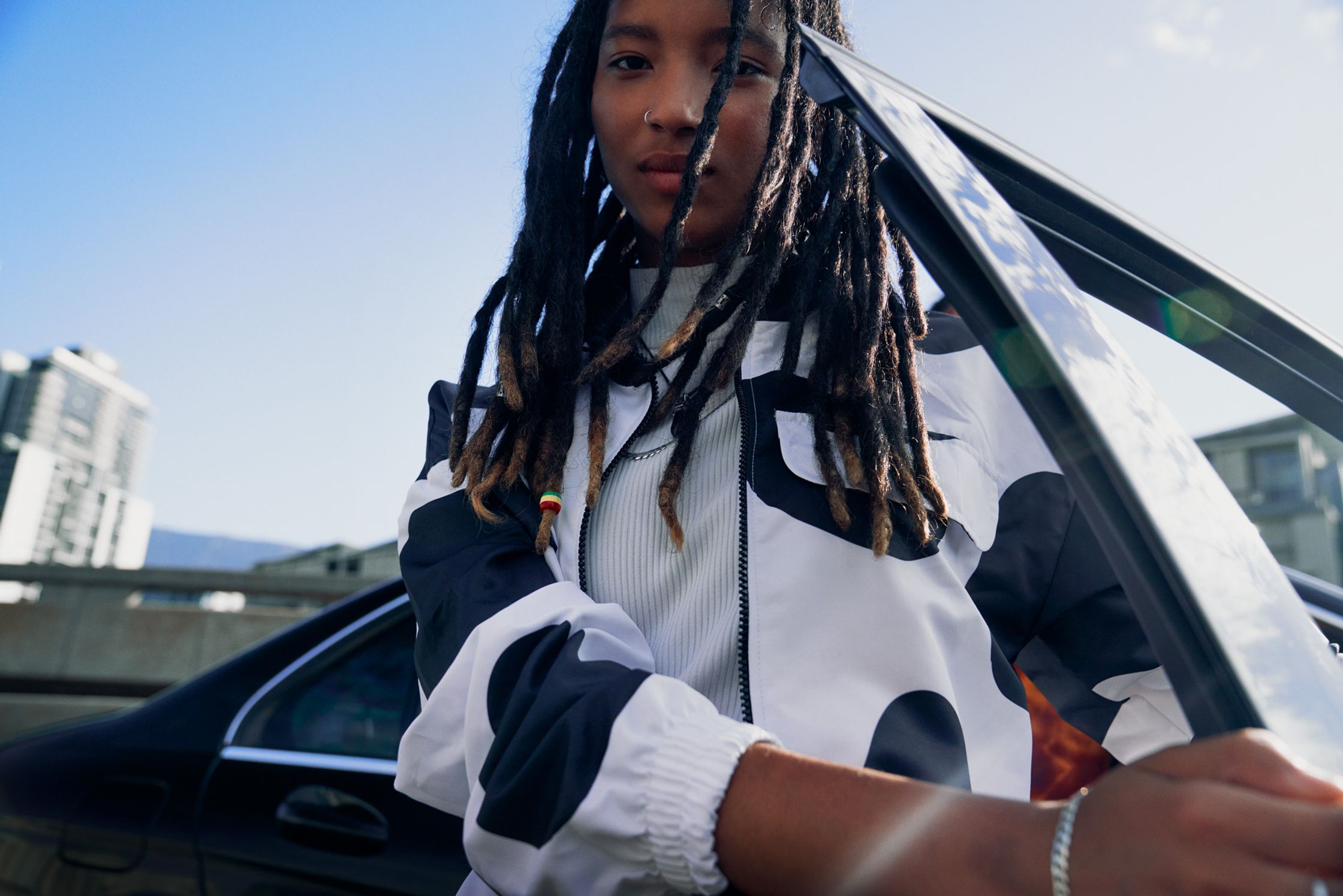 a young woman with dreadlocks standing next to a car