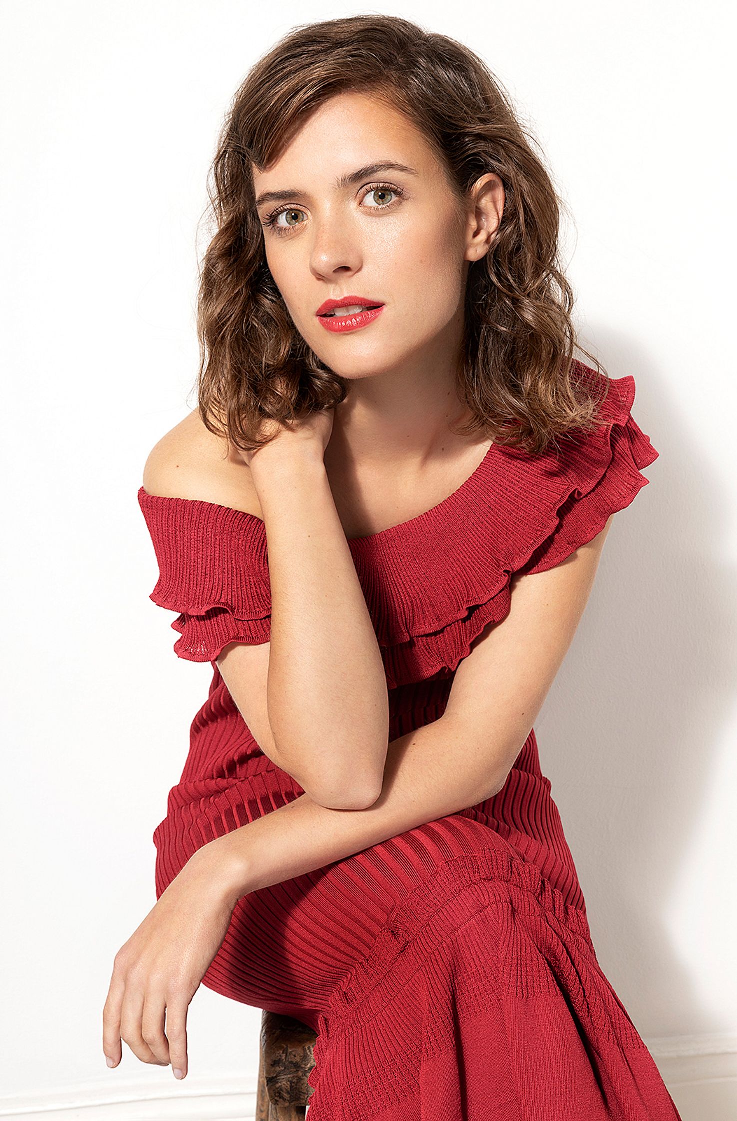 liv lisa fries in a red dress posing on a stool