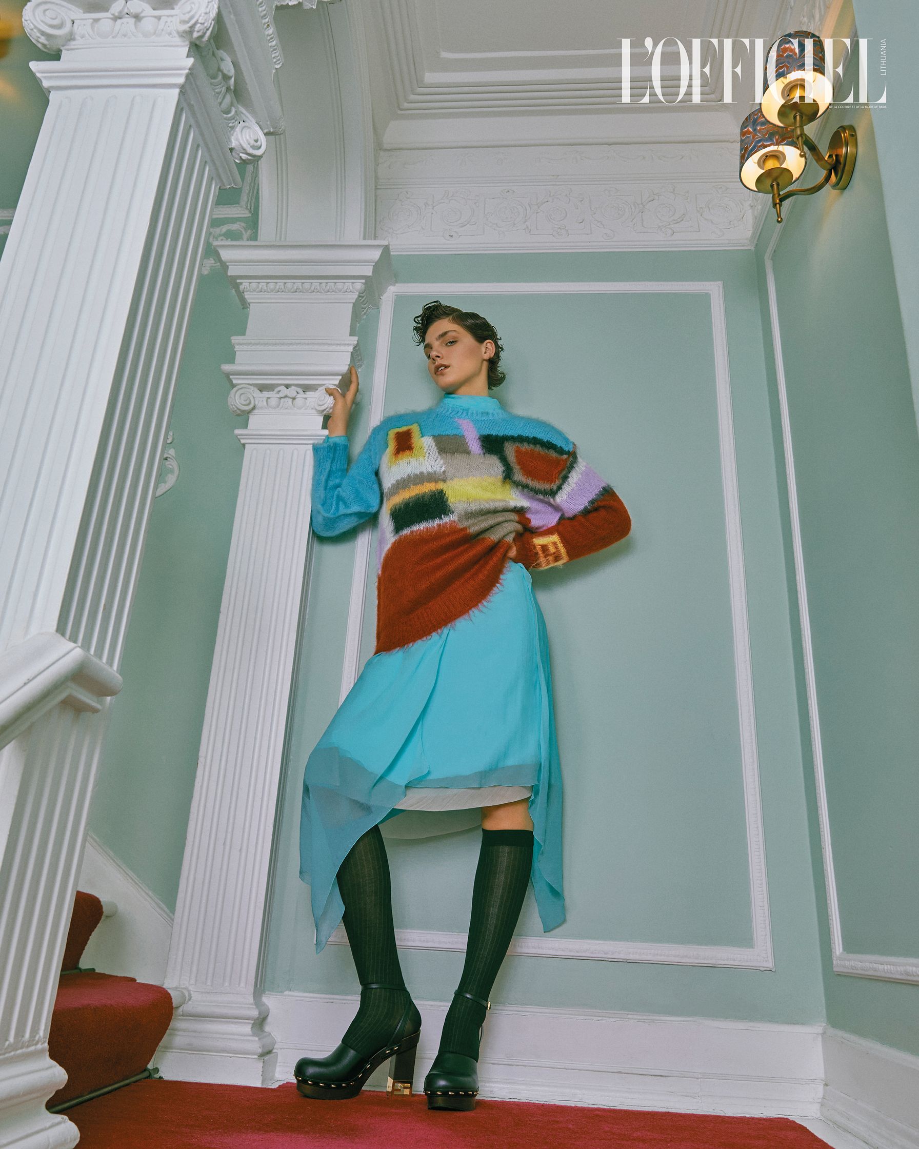 a woman is posing in front of a staircase