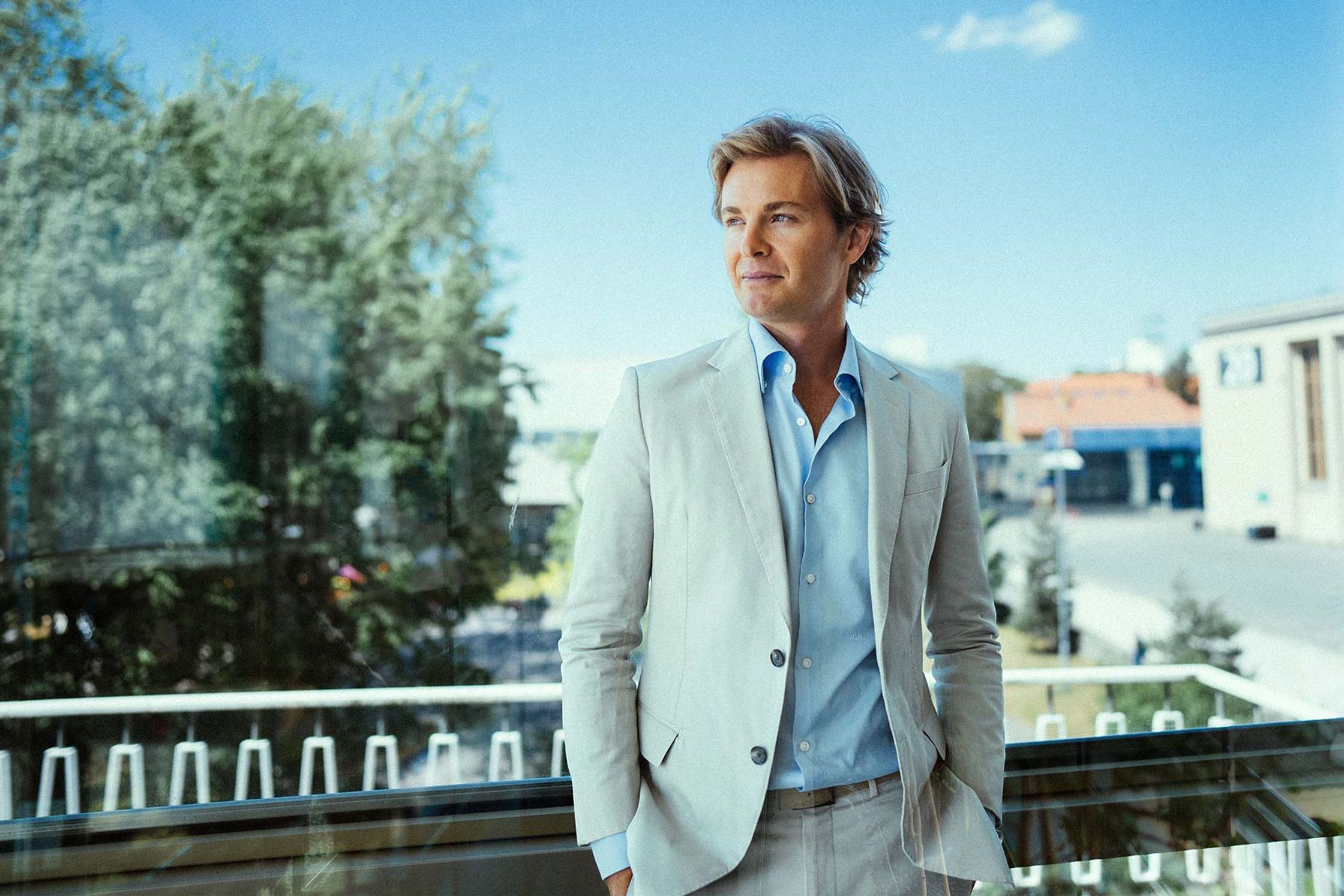 Nico Rosberg in a white suit standing on a balcony