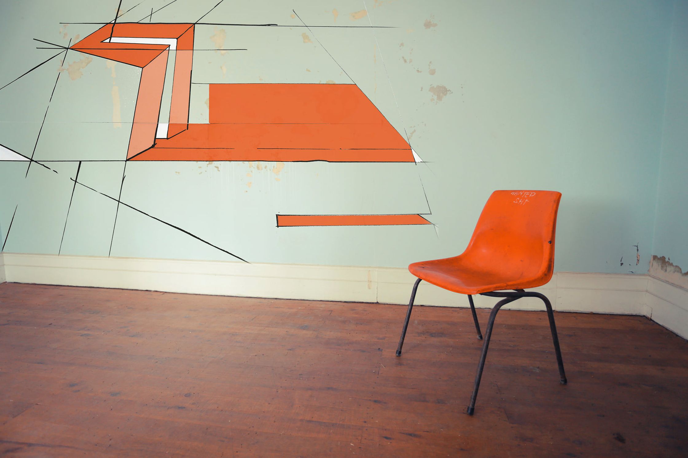 an orange chair in a room with a blue wall