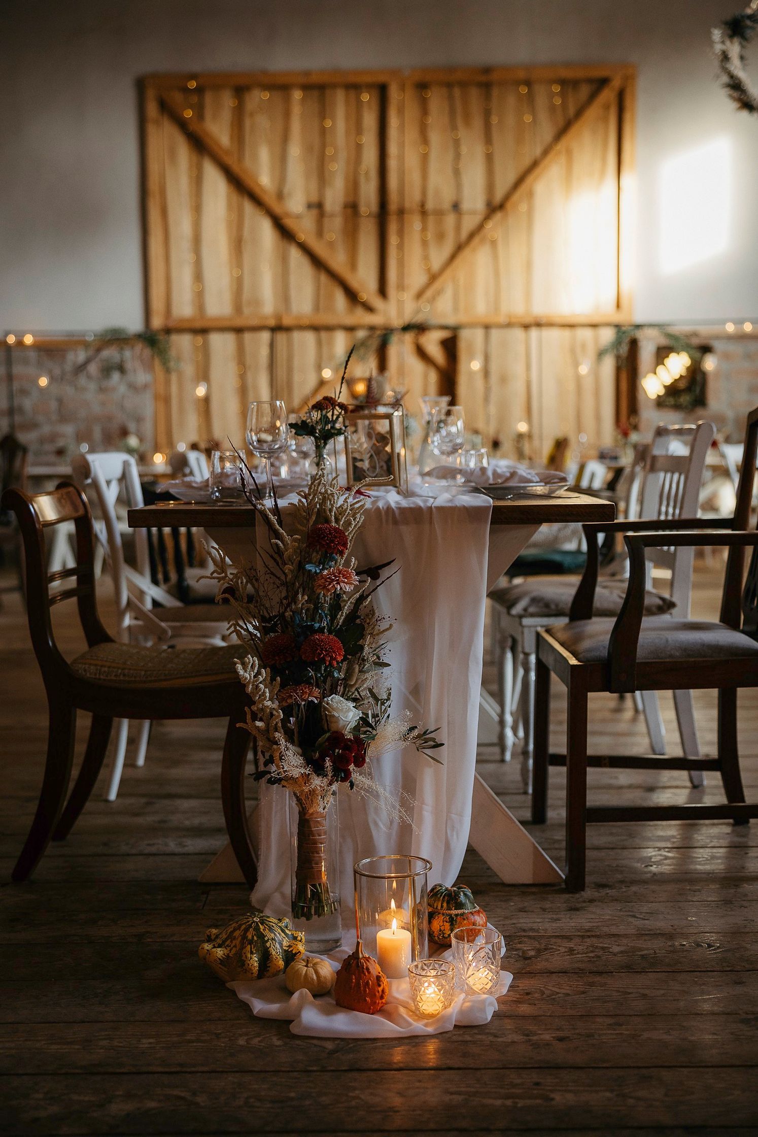 Ein in einer Scheune gedeckter Hochzeitstisch mit Kerzen