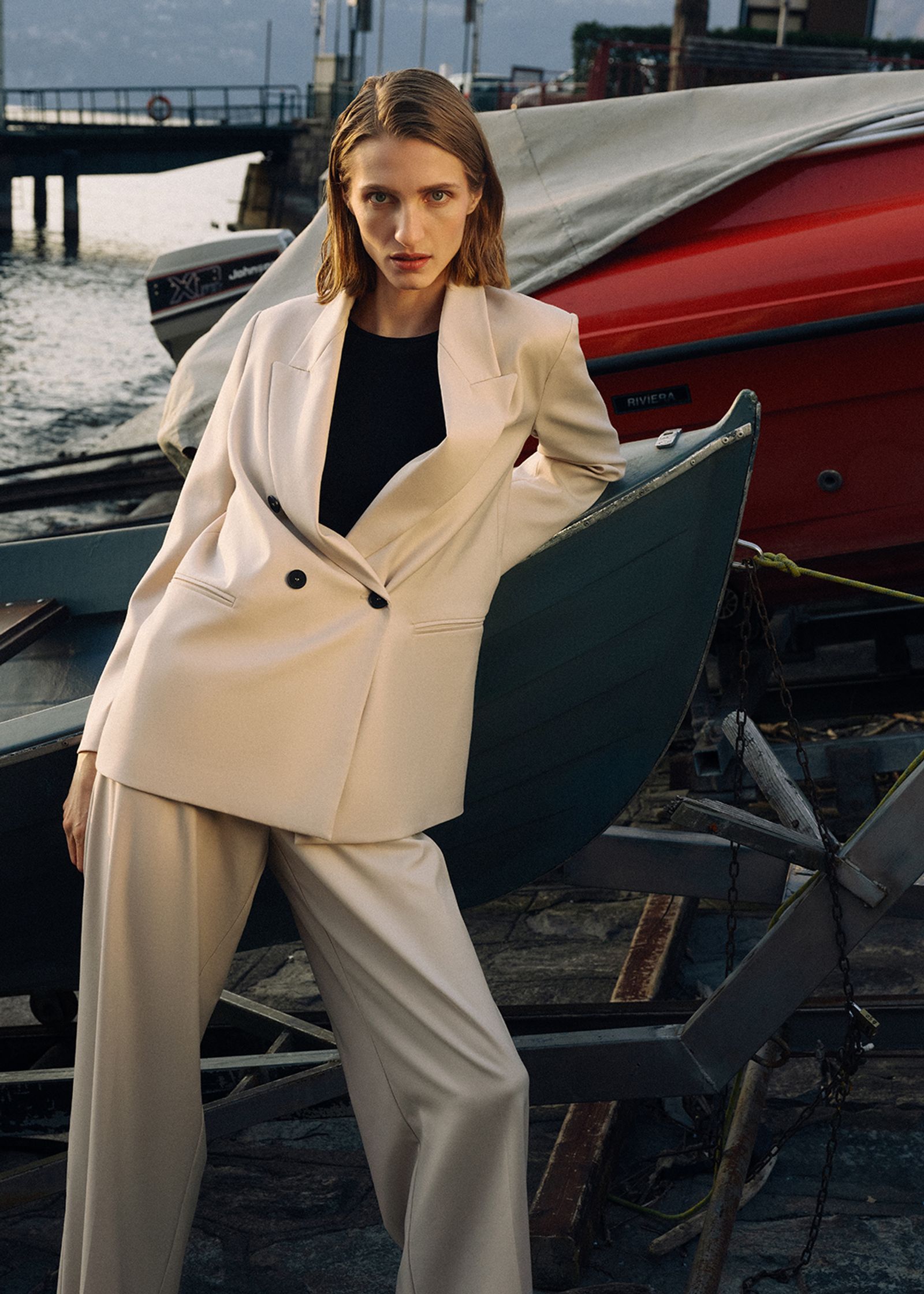 a woman in a white suit posing next to a boat