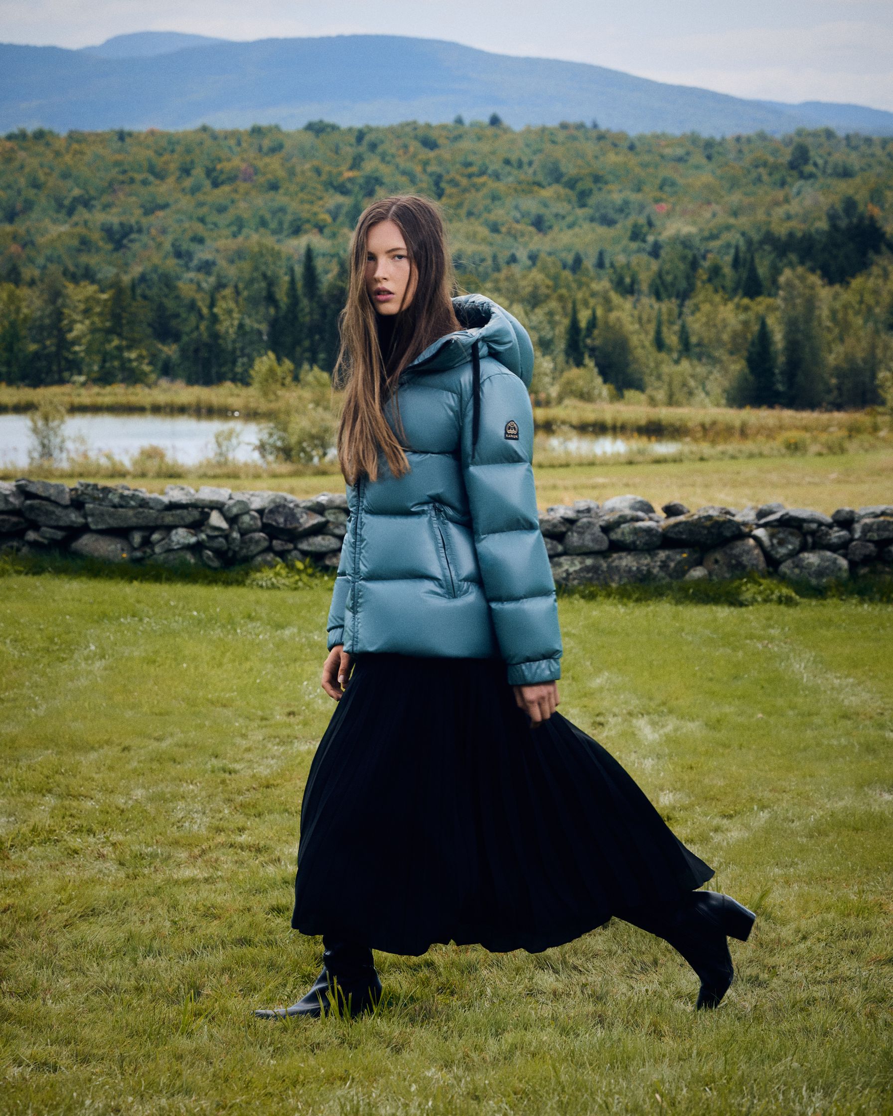 a woman in a blue puffer jacket walking in a field