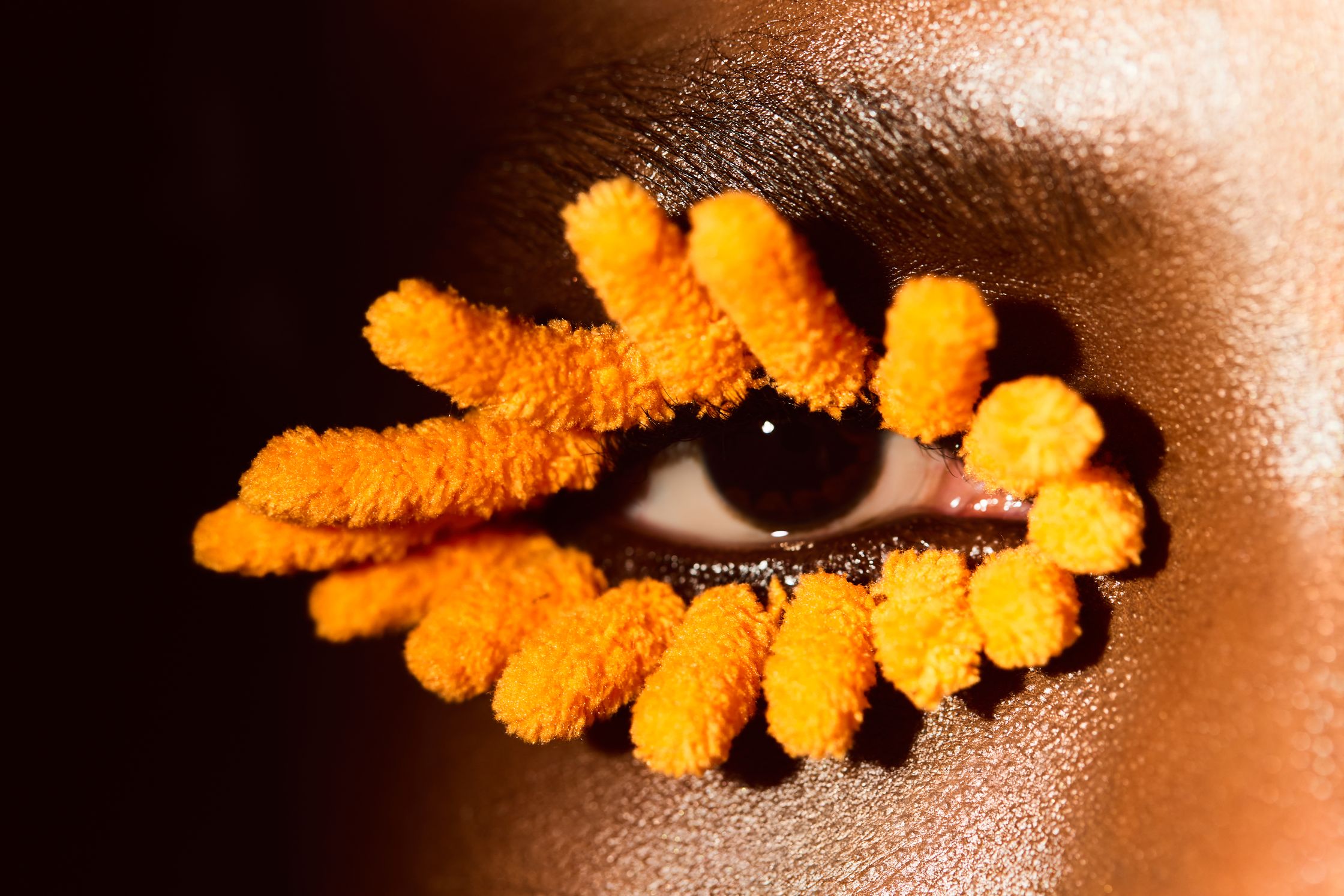 a close up of a woman's eye with orange eyelashes