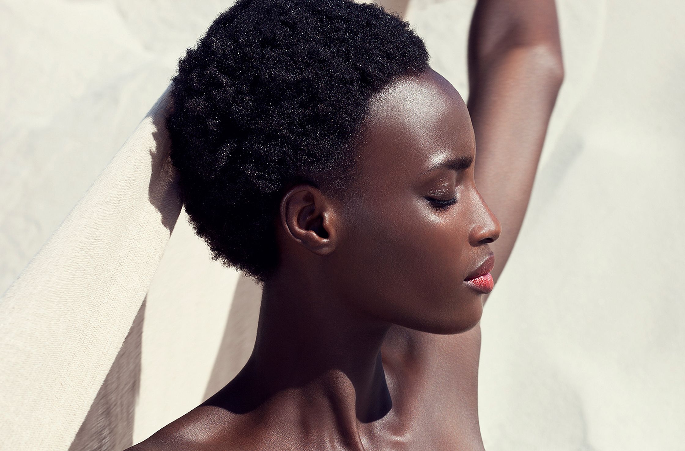 a black woman is laying on a towel in the sand skin retouch