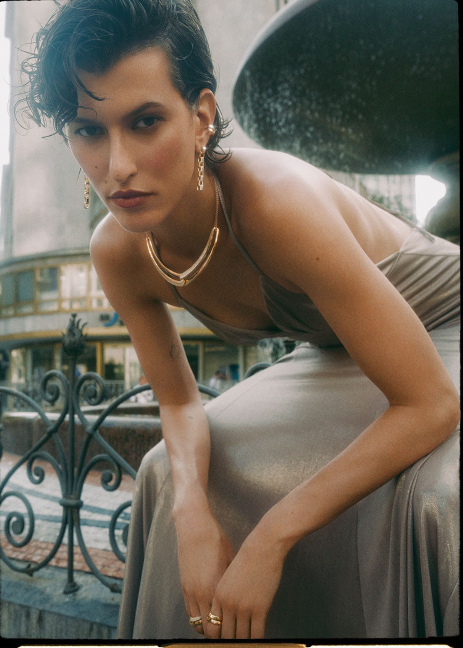 a woman in a dress is posing in front of a fountain