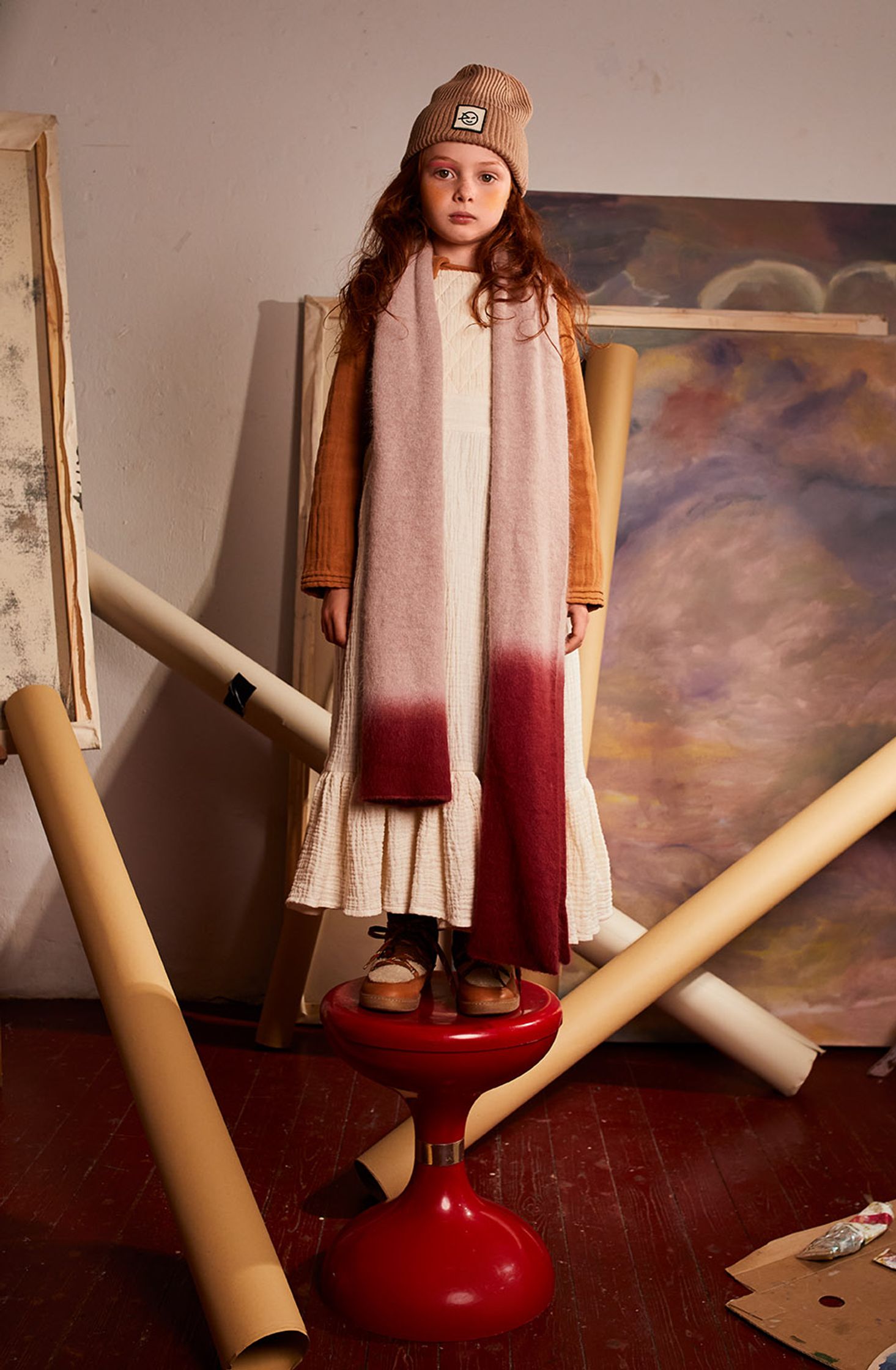 a little girl standing on a stool in front of a painting