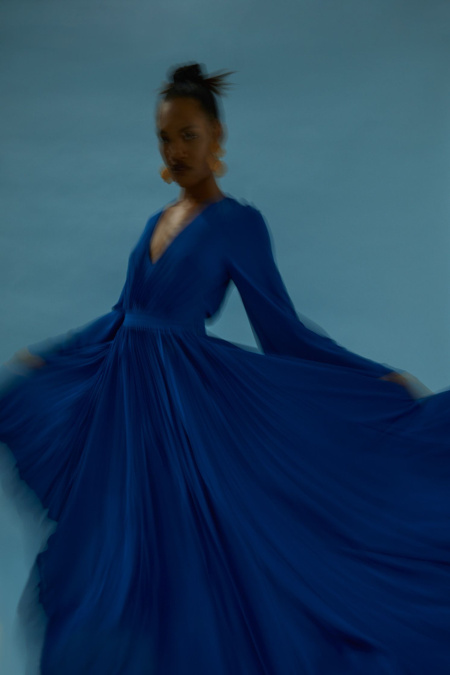 a woman in a blue dress is dancing on a blue background