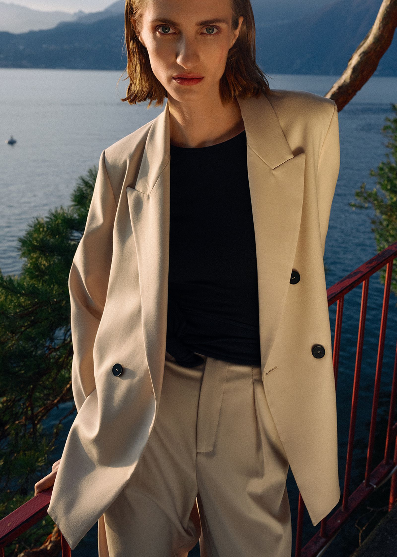 a model wearing a beige suit and a black top