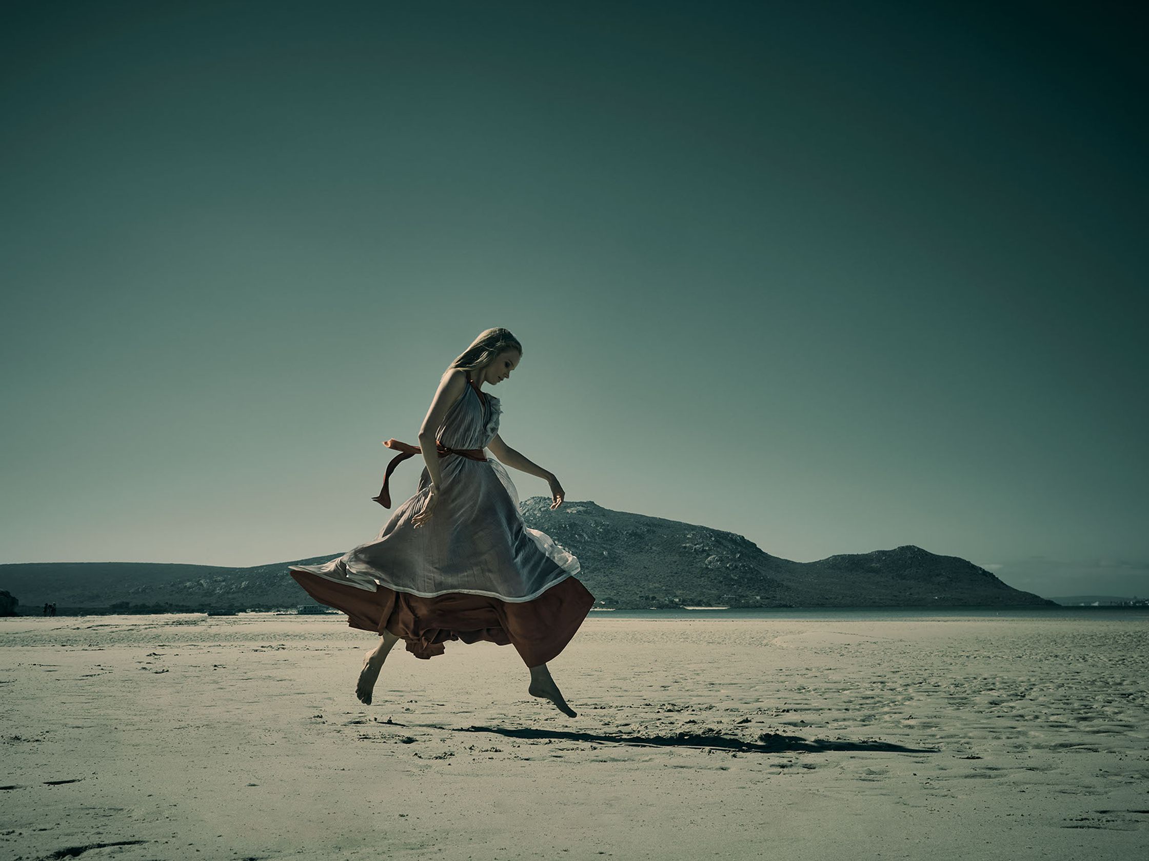 a woman in a long dress is running on the beach