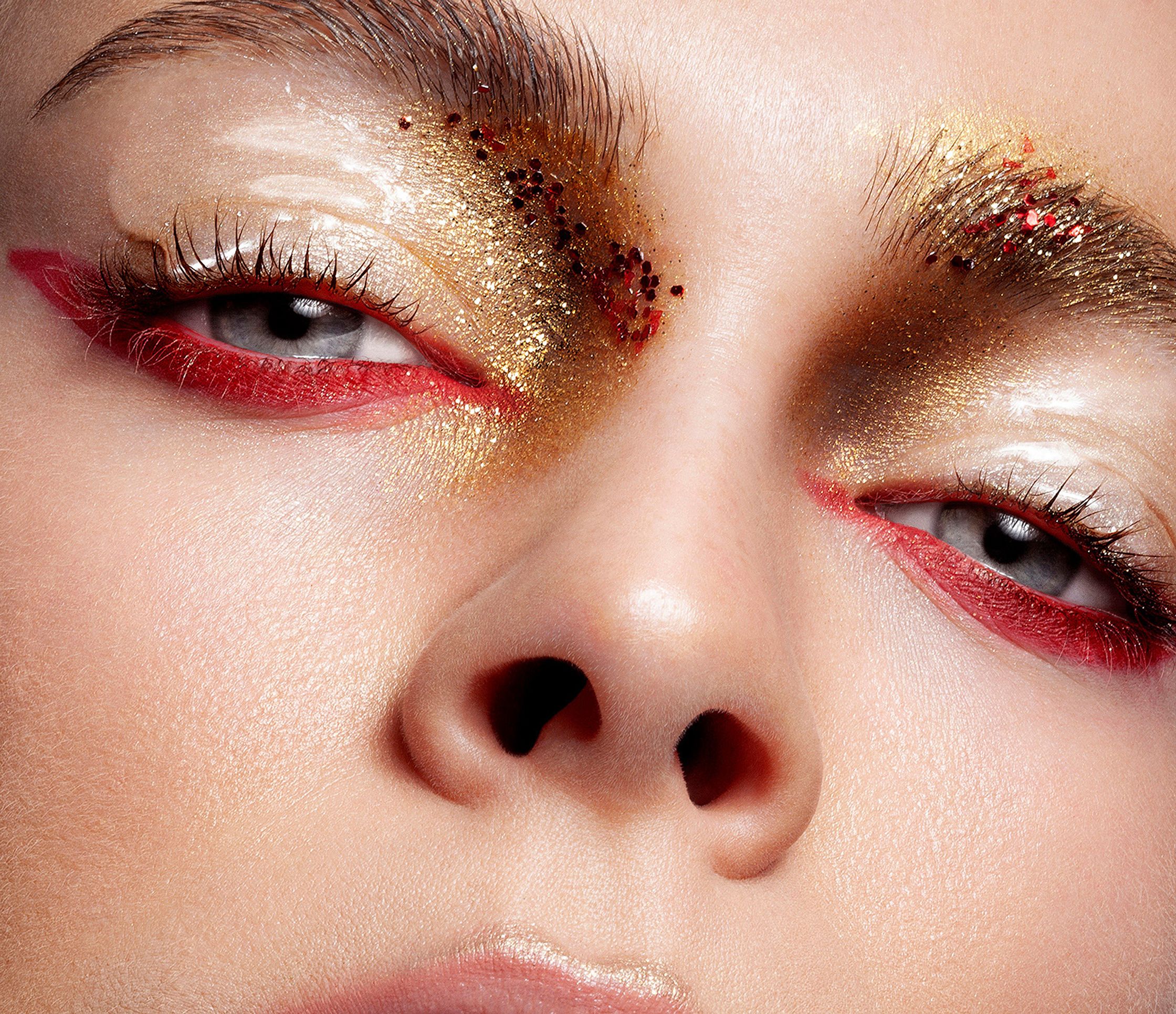 a close up of a woman's face with gold and red eye makeup beauty post production