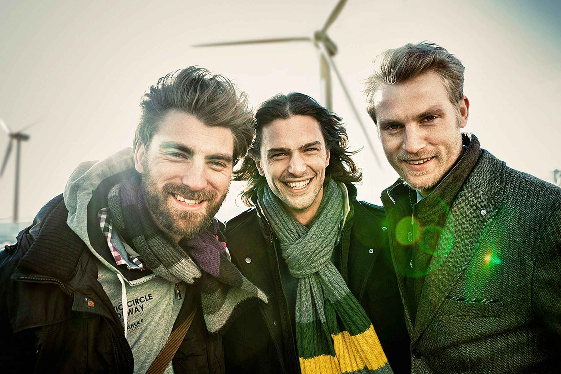 three men smiling in front of wind turbines Bildbearbeitung calamar fashion kampagne