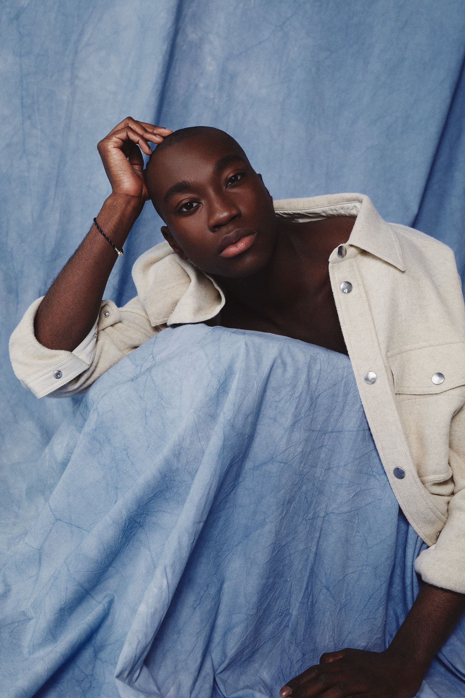 a black man posing on a blue cloth