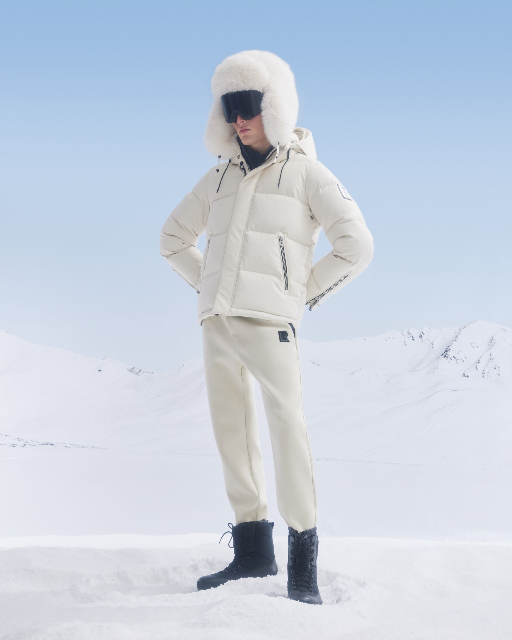 a man in a white puffer jacket standing in the snow