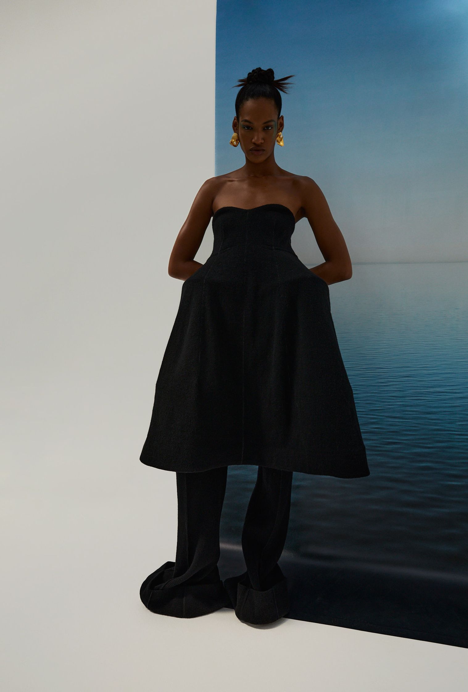 a woman in a black dress standing next to a body of water