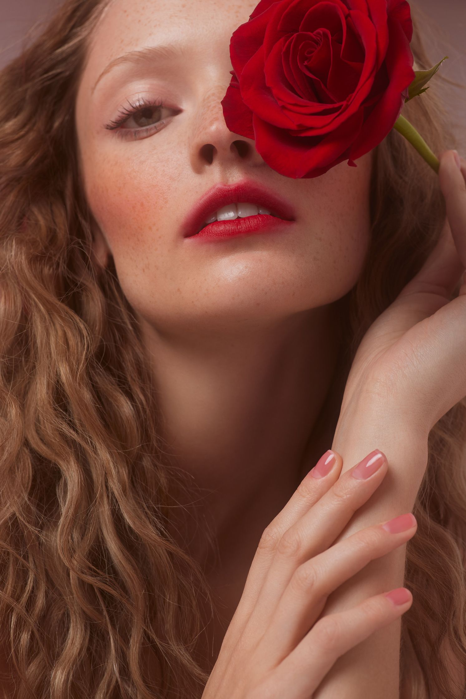 a beautiful woman with curly hair holding a red rose